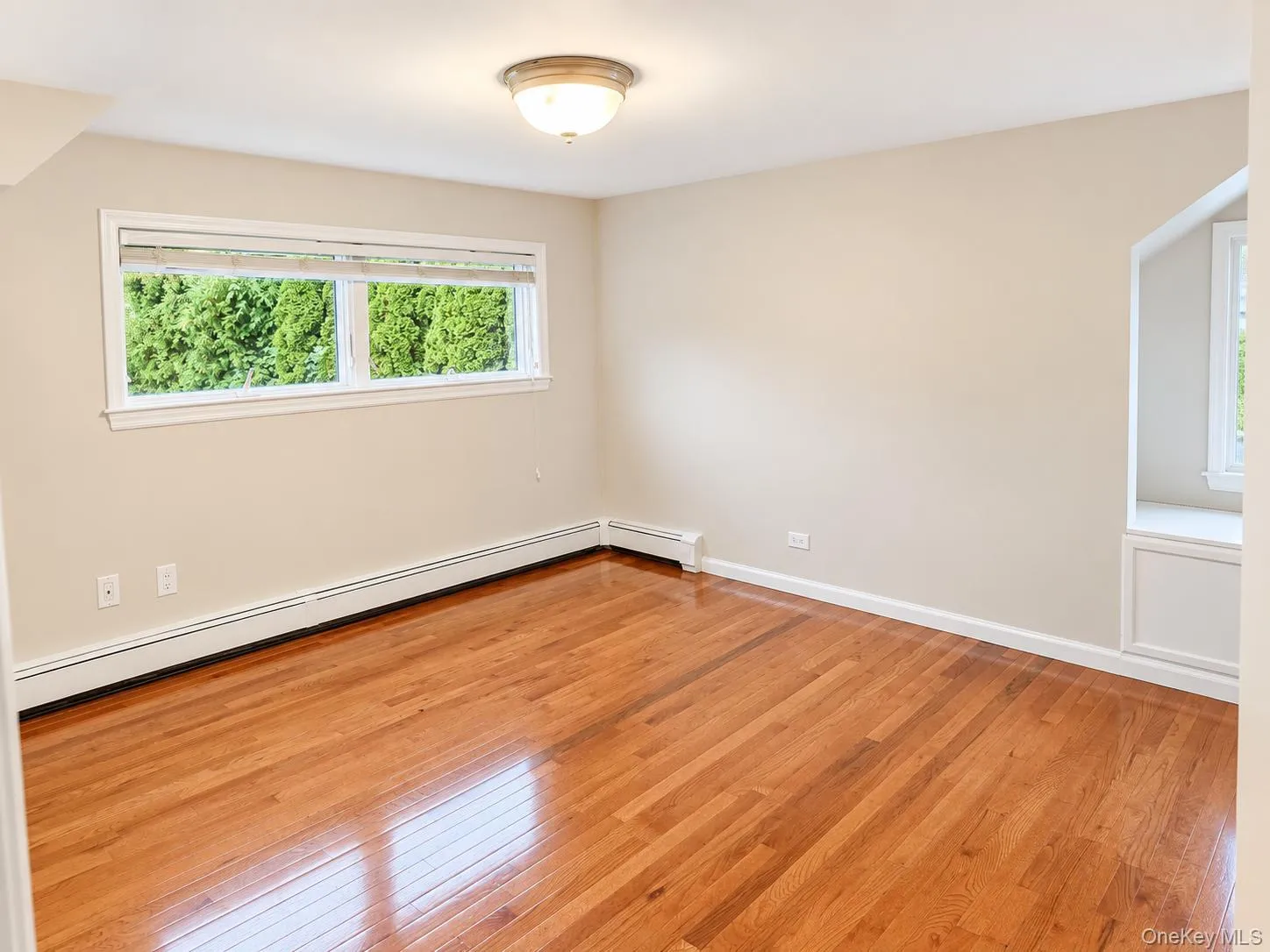 Hardwood flooring, neutral wall tones, double window, built-in window seat, and ceiling-mounted light fixture Hardwood flooring, neutral wall tones, double window, built-in window seat, and ceiling-mounted light fixture