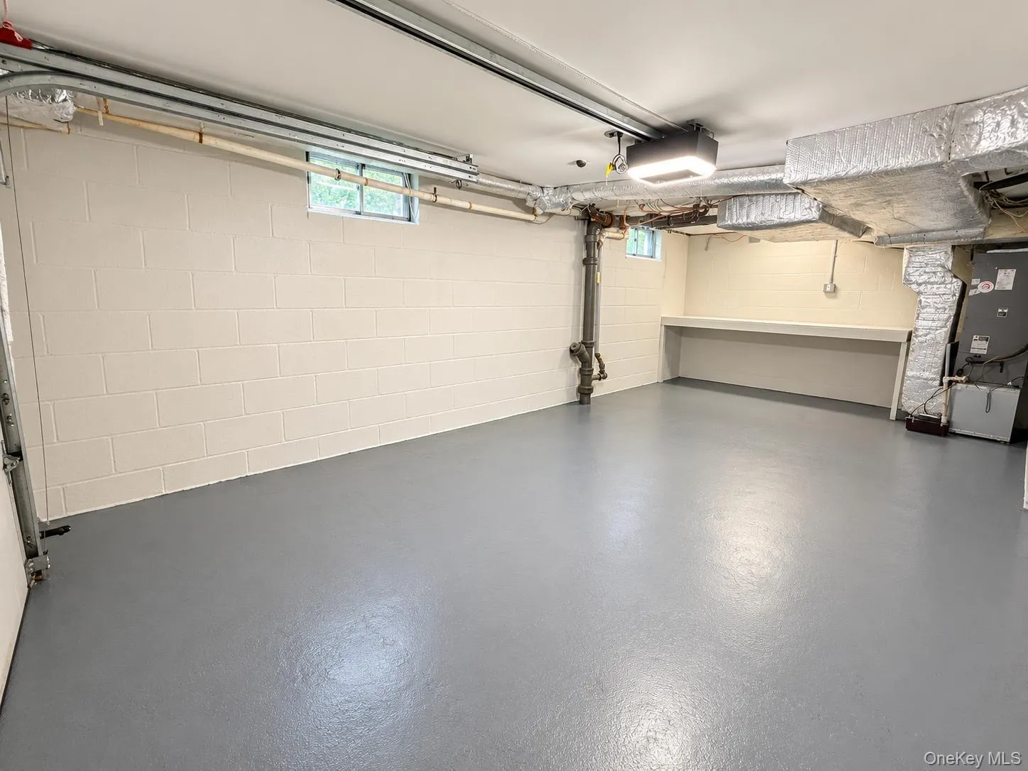 Clean-finished concrete block walls with windows, painted concrete flooring, and a built-in workbench Clean-finished concrete block walls with windows, painted concrete flooring, and a built-in workbench