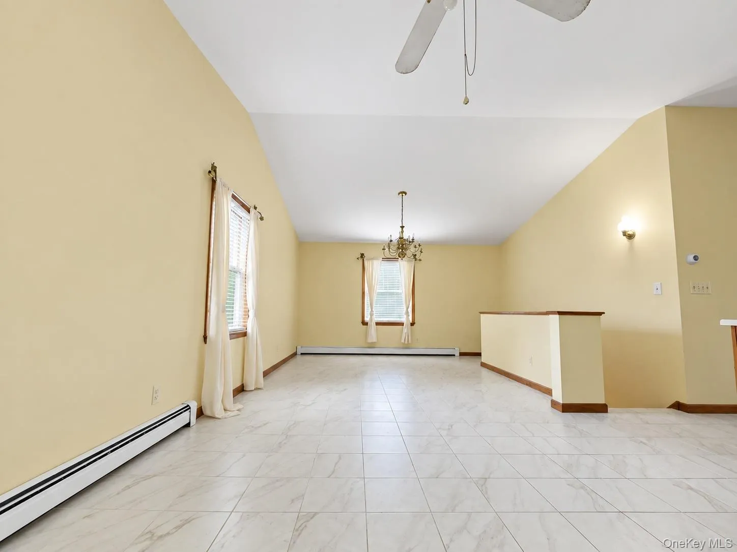 Vaulted ceiling with a ceiling fan, white tile flooring, and a chandelier Vaulted ceiling with a ceiling fan, white tile flooring, and a chandelier