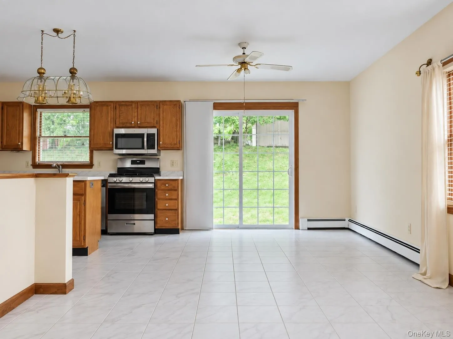 White tile flooring with a kitchen featuring wood cabinetry and stainless steel appliances White tile flooring with a kitchen featuring wood cabinetry and stainless steel appliances