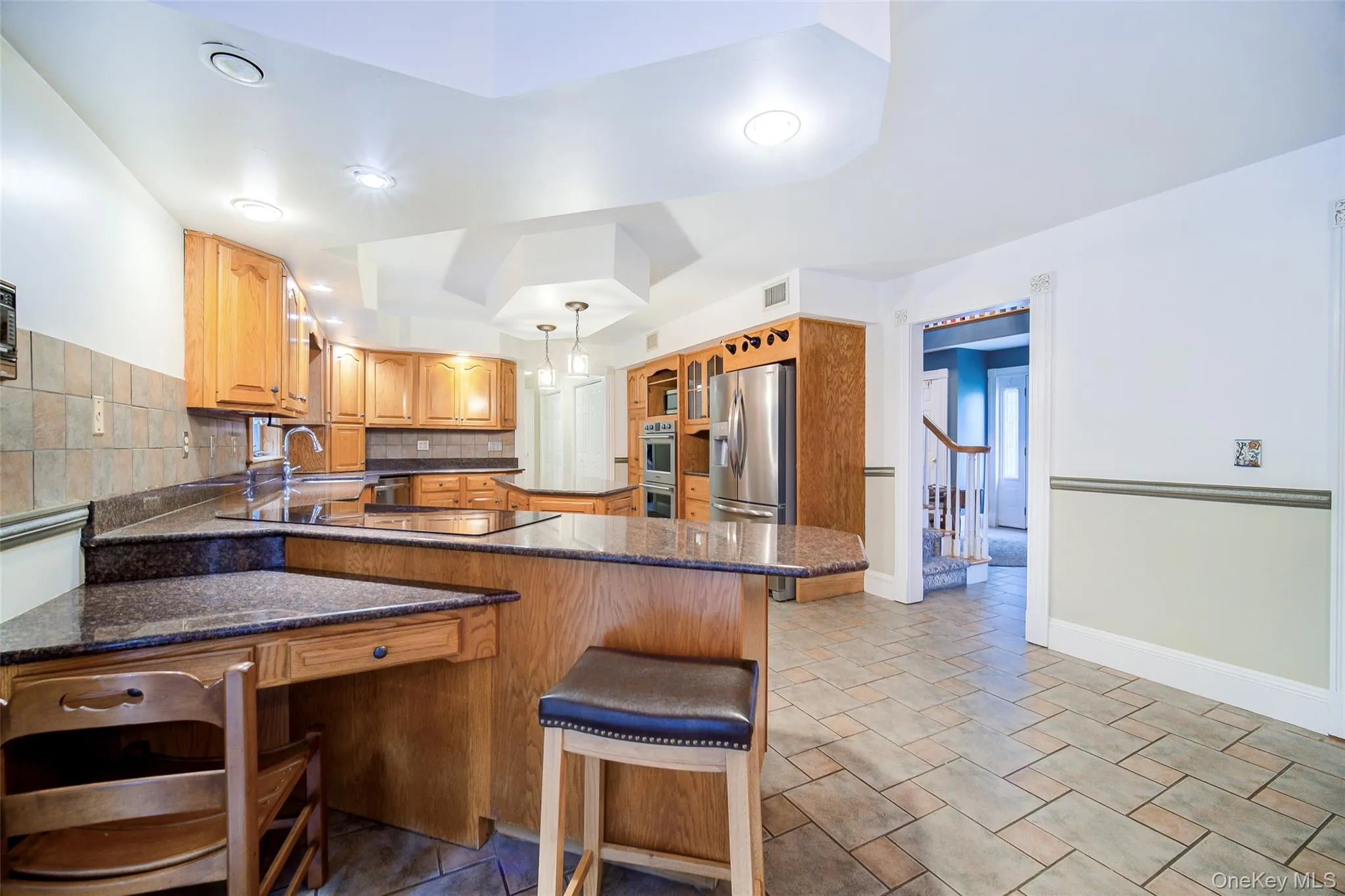 Kitchen features a tiled backsplash, custom lighting, and abundant counter space, including this perfect work area. Kitchen features a tiled backsplash, custom lighting, and abundant counter space, including this perfect work area.
