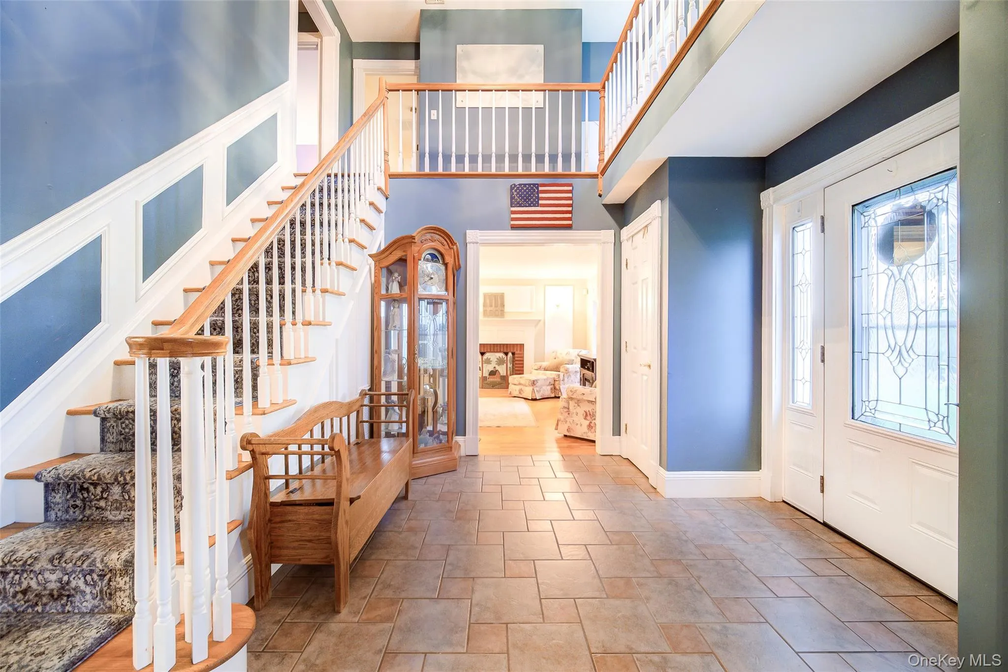 Two-story foyer featuring tile flooring and a grand staircase with wood-finish handrails and custom molding Two-story foyer featuring tile flooring and a grand staircase with wood-finish handrails and custom molding