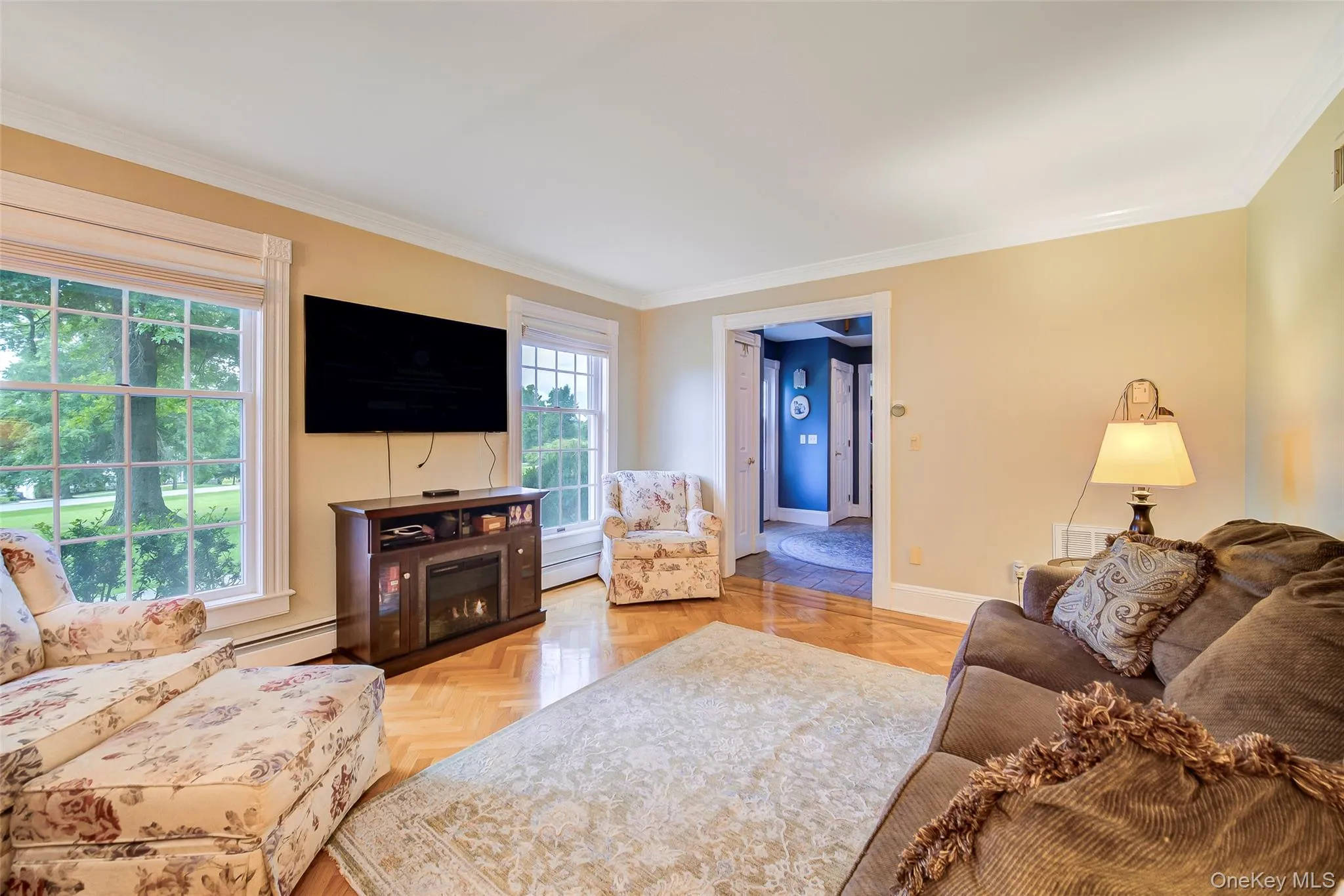 Spacious living room featuring hardwood flooring, large multi-pane windows with natural light, and warm yellow-toned walls throughout the room Spacious living room featuring hardwood flooring, large multi-pane windows with natural light, and warm yellow-toned walls throughout the room