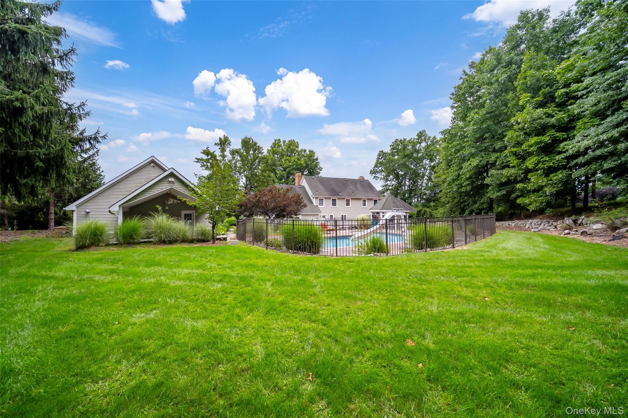 Expansive lawn area featuring a fenced swimming pool, adjacent gazebo, and a secondary garage structure with covered entry Expansive lawn area featuring a fenced swimming pool, adjacent gazebo, and a secondary garage structure with covered entry