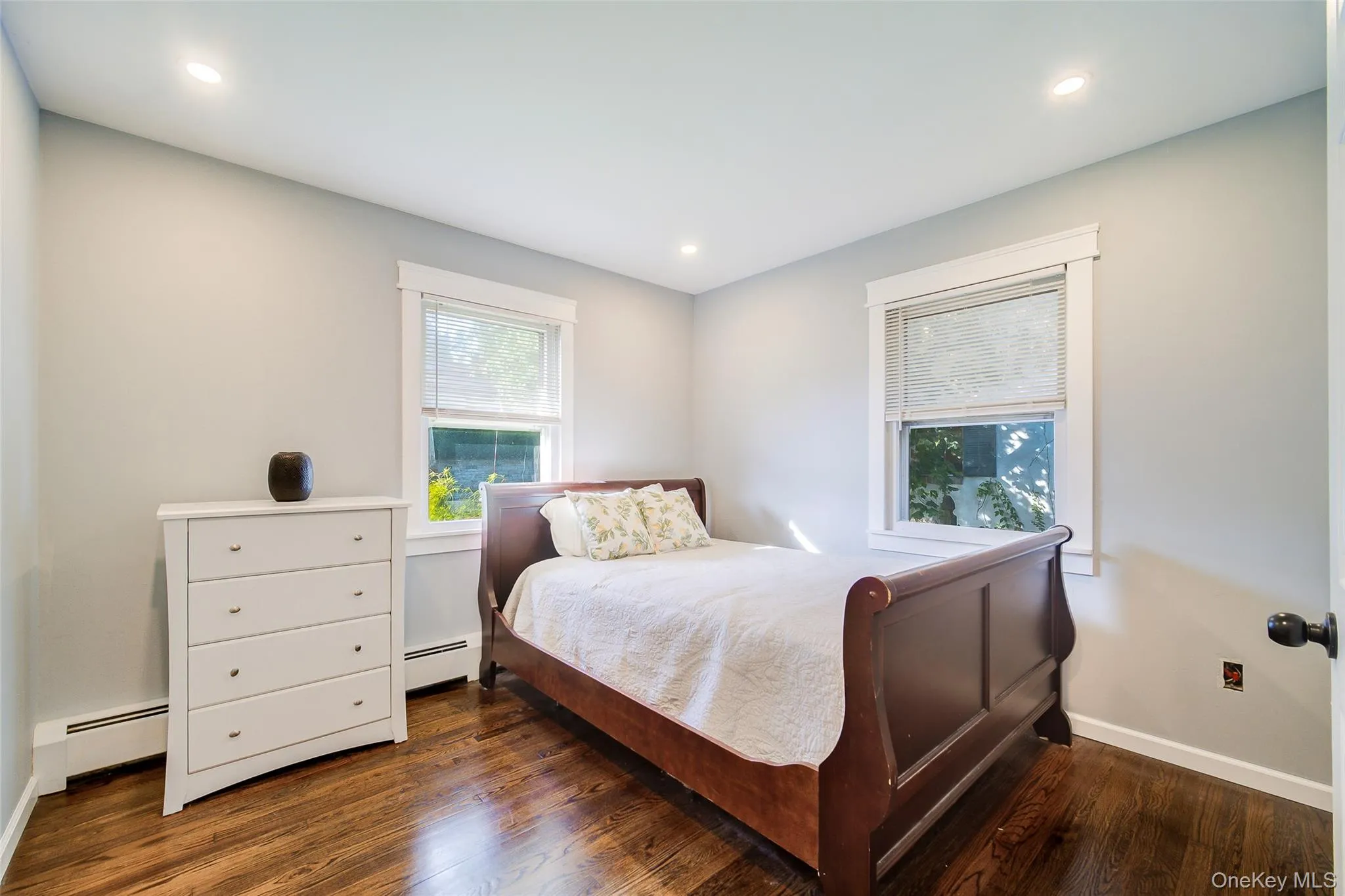 Recessed ceiling lighting, two windows with white trim, light gray painted walls, and wood-finish flooring Recessed ceiling lighting, two windows with white trim, light gray painted walls, and wood-finish flooring