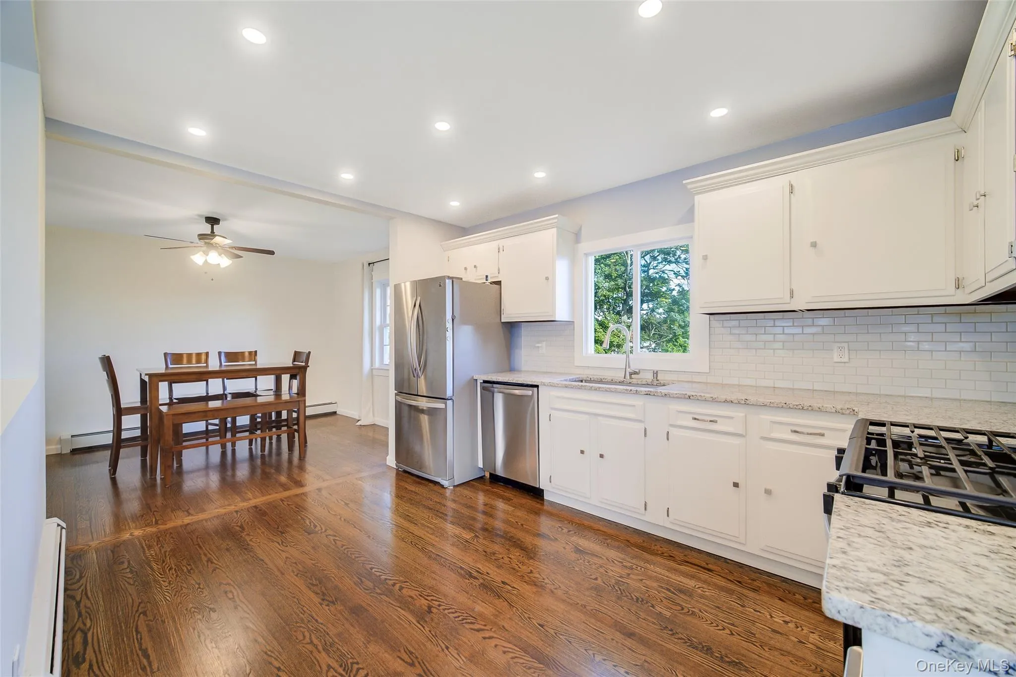 Kitchen featuring white cabinetry, beautiful granite countertops, stainless steel appliances, and a subway tile backsplash Kitchen featuring white cabinetry, beautiful granite countertops, stainless steel appliances, and a subway tile backsplash