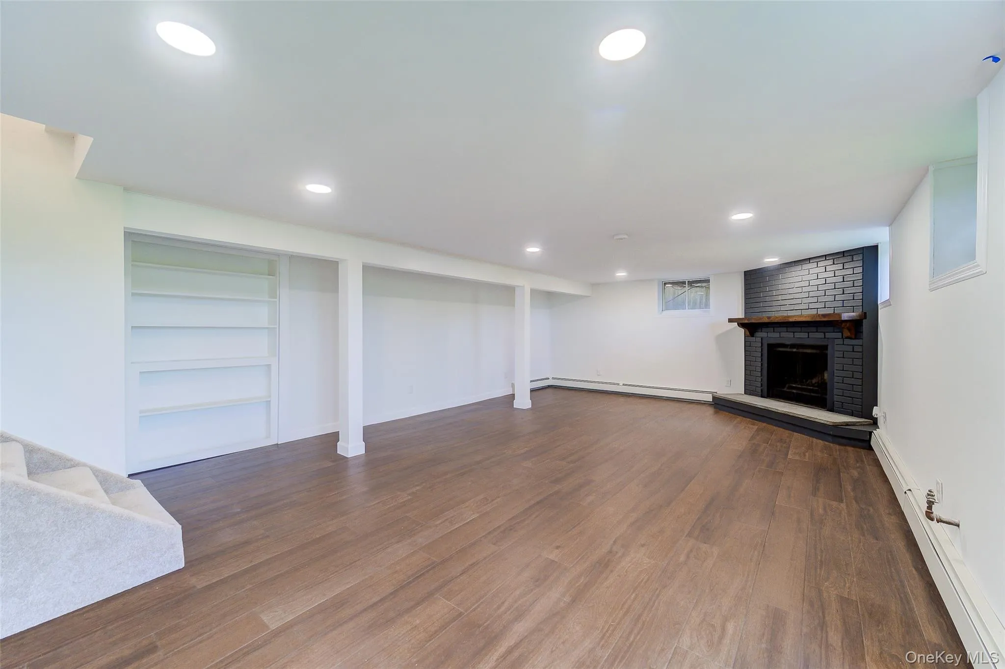 Located on lower level, newly updated finish room with wood-finish flooring, recessed lighting, and custom built-in shelving Located on lower level, newly updated finish room with wood-finish flooring, recessed lighting, and custom built-in shelving