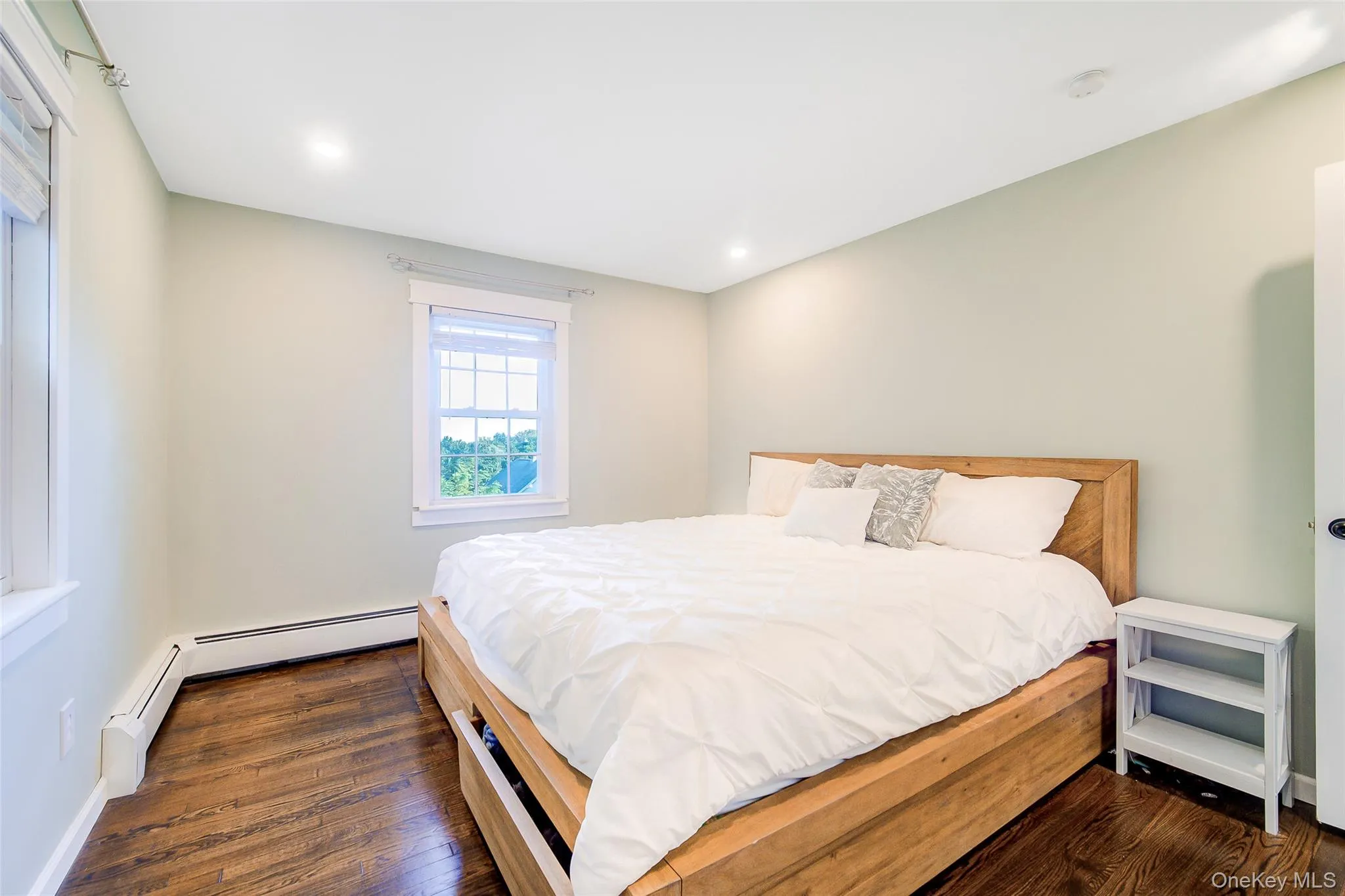 Spacious primary bedroom has recessed lighting, hardwood flooring, (king size bed in photo) Spacious primary bedroom has recessed lighting, hardwood flooring, (king size bed in photo)