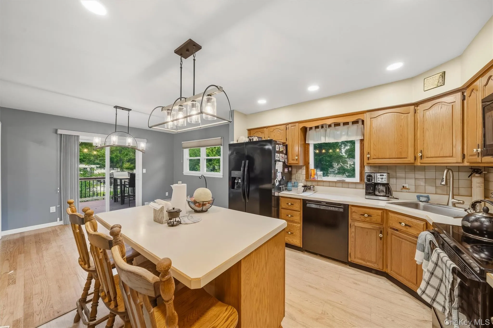 Kitchen with light-toned wood-finish flooring, a center island with counter seating, and light wood cabinetry Kitchen with light-toned wood-finish flooring, a center island with counter seating, and light wood cabinetry