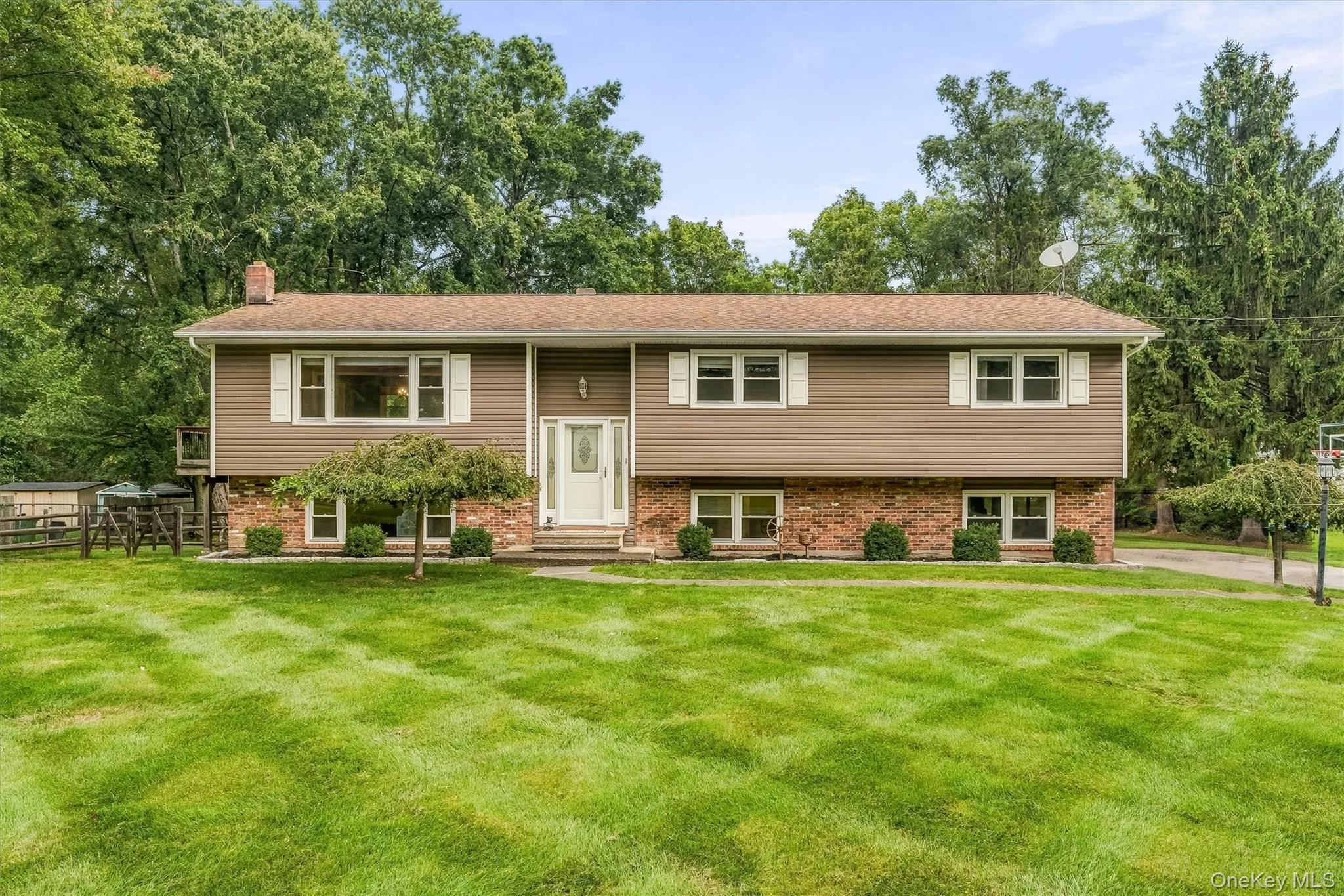 Split-level residence featuring brick and siding facade, contrasting white window shutters, and a white front entry door Split-level residence featuring brick and siding facade, contrasting white window shutters, and a white front entry door