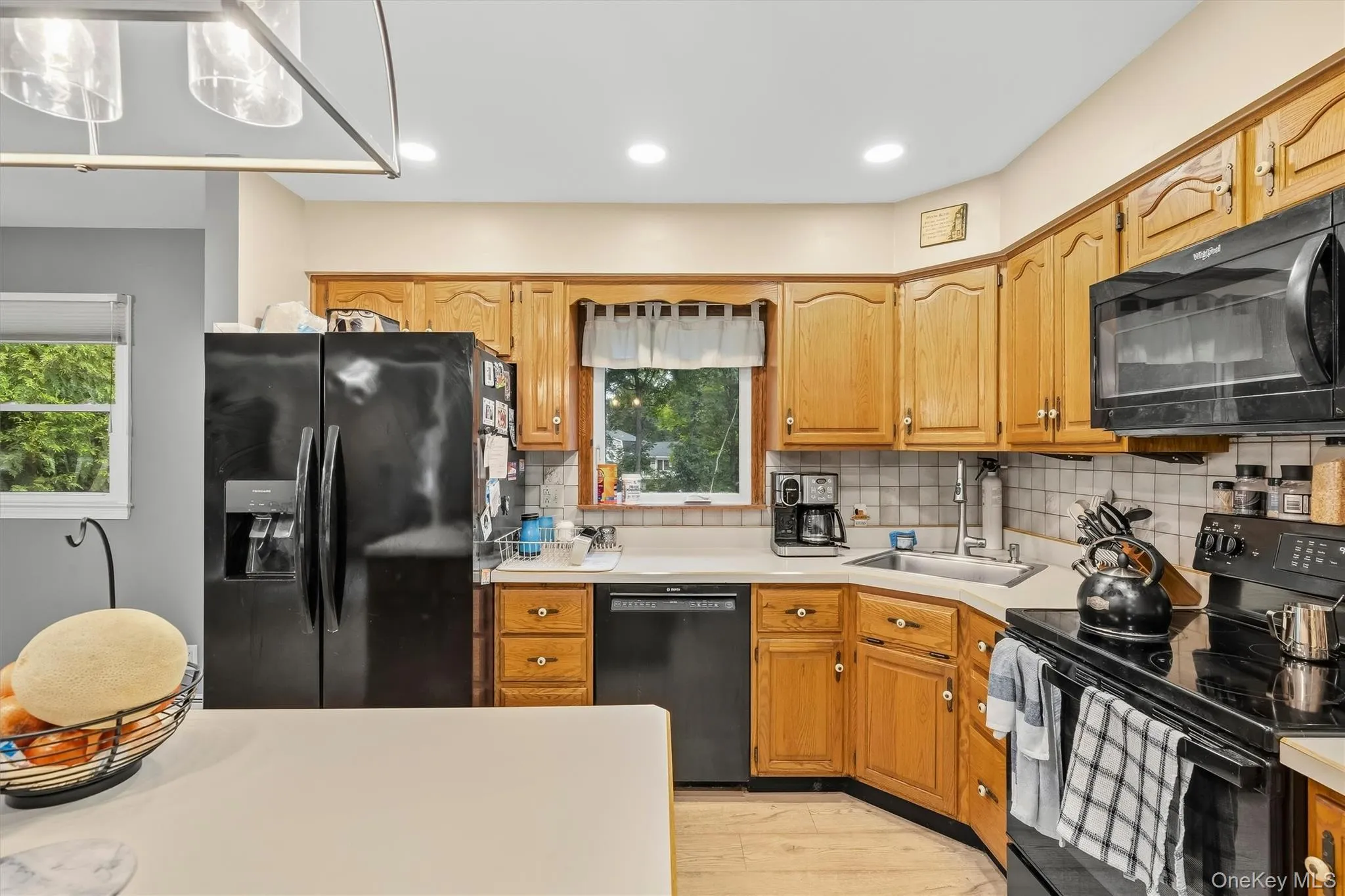 Kitchen featuring wood-finish cabinetry, black appliances, recessed lighting, and a tile backsplash Kitchen featuring wood-finish cabinetry, black appliances, recessed lighting, and a tile backsplash