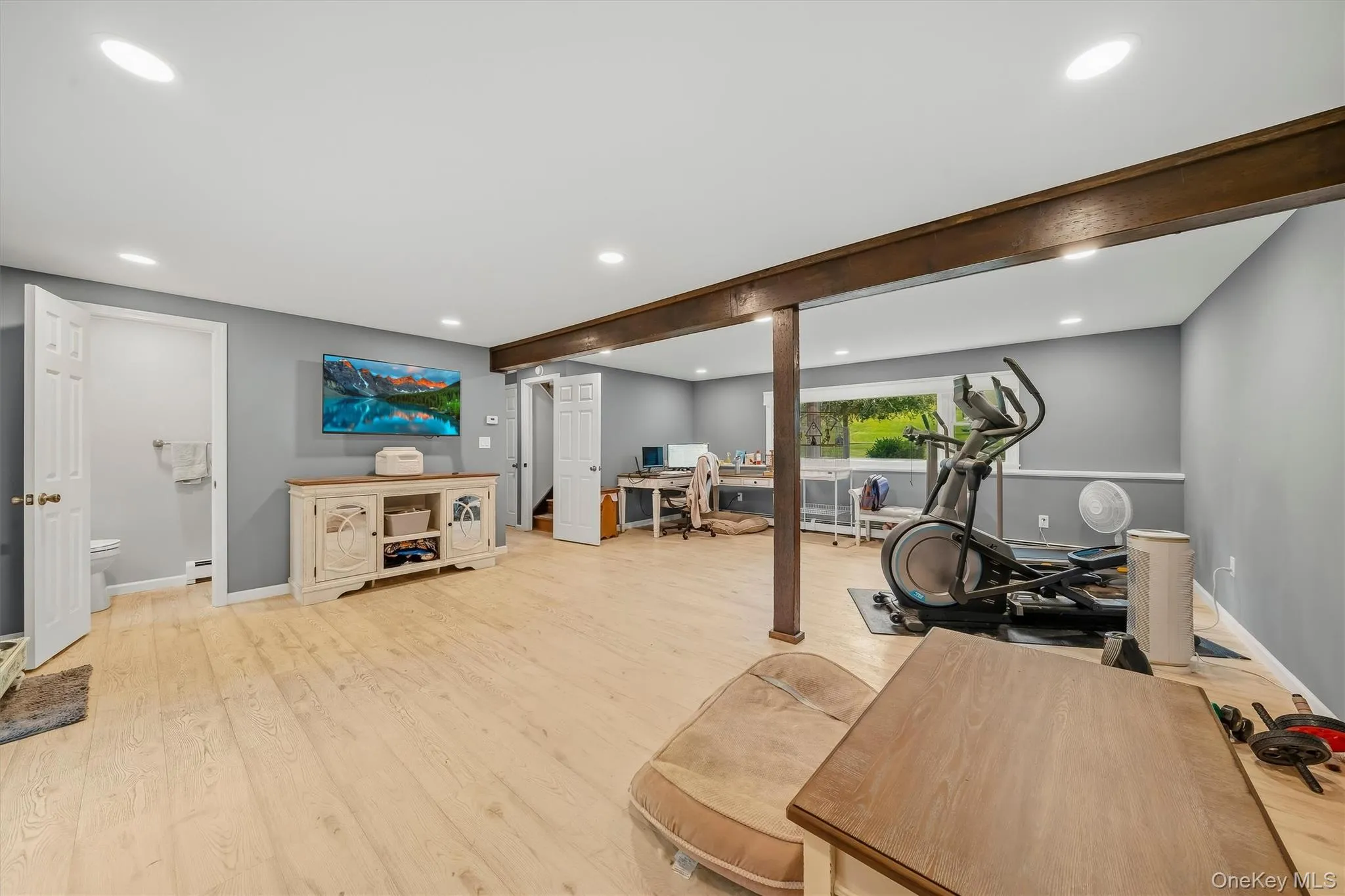 Recessed ceiling lighting, wood-finish flooring, exposed wood beam, large windows, and a separate room with a toilet and towel bar Recessed ceiling lighting, wood-finish flooring, exposed wood beam, large windows, and a separate room with a toilet and towel bar
