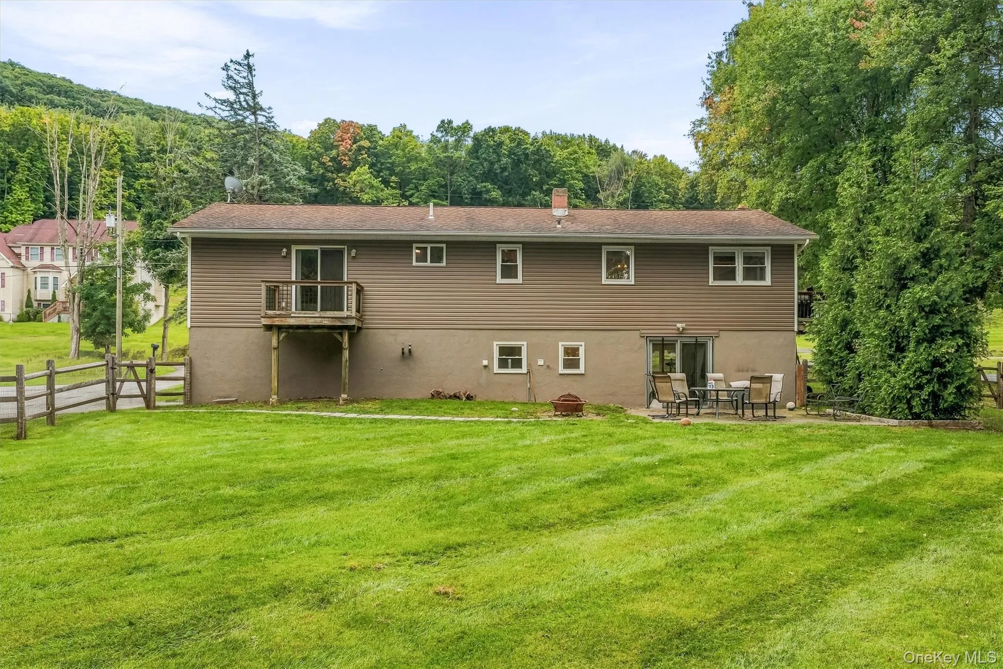 Expansive green lawn with a split-rail fence, rear balcony, and lower-level patio area Expansive green lawn with a split-rail fence, rear balcony, and lower-level patio area