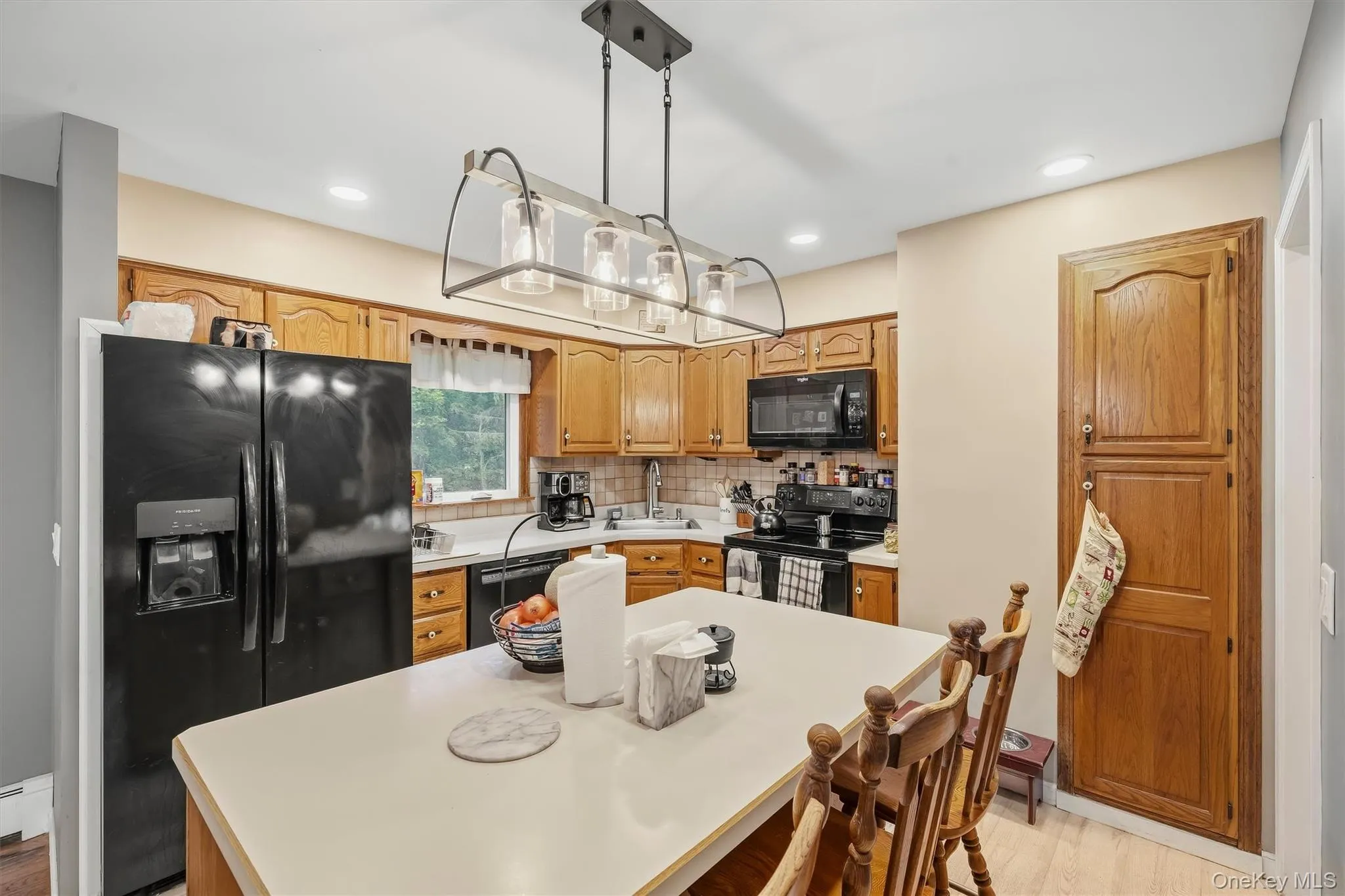 Kitchen featuring wood cabinetry, a center island with seating, a black side-by-side refrigerator, a black microwave, and a black range Kitchen featuring wood cabinetry, a center island with seating, a black side-by-side refrigerator, a black microwave, and a black range