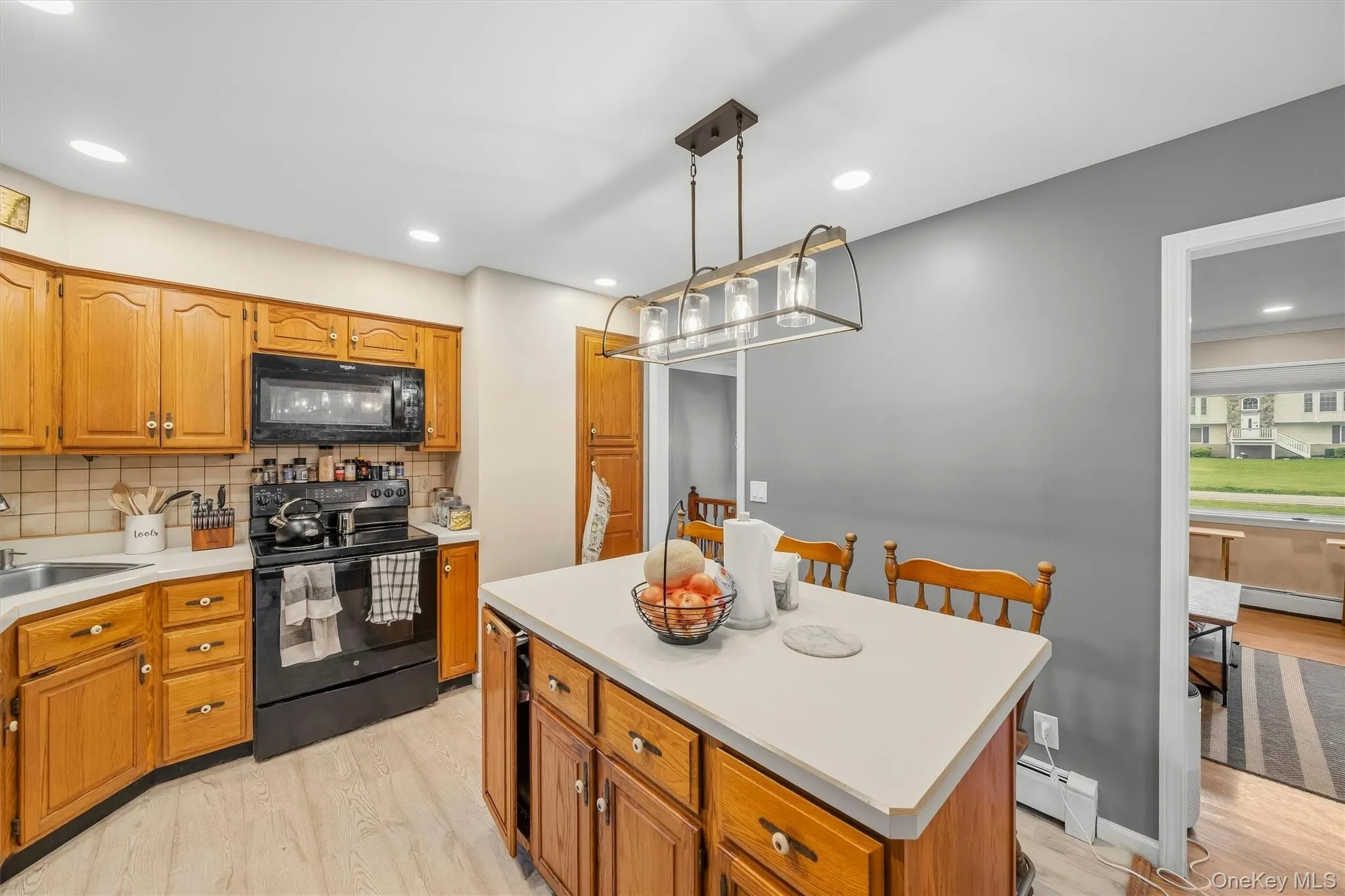 Kitchen featuring wood cabinetry, light-colored countertops, black appliances, and recessed lighting Kitchen featuring wood cabinetry, light-colored countertops, black appliances, and recessed lighting
