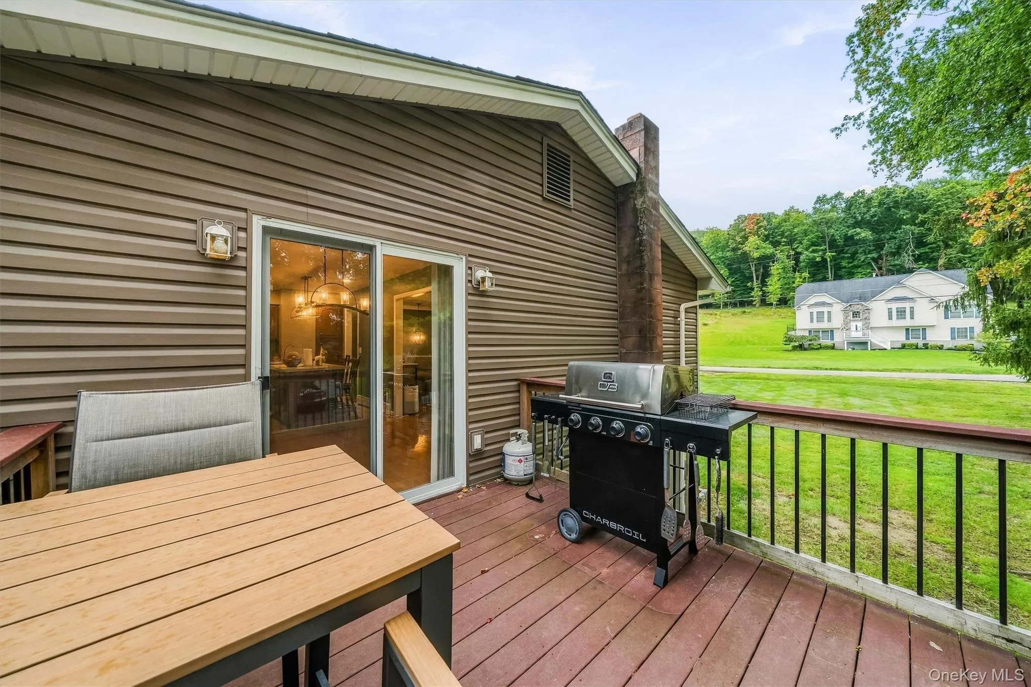 Expansive rear deck with wood-finish flooring, black spindle railing, and sliding glass door access Expansive rear deck with wood-finish flooring, black spindle railing, and sliding glass door access