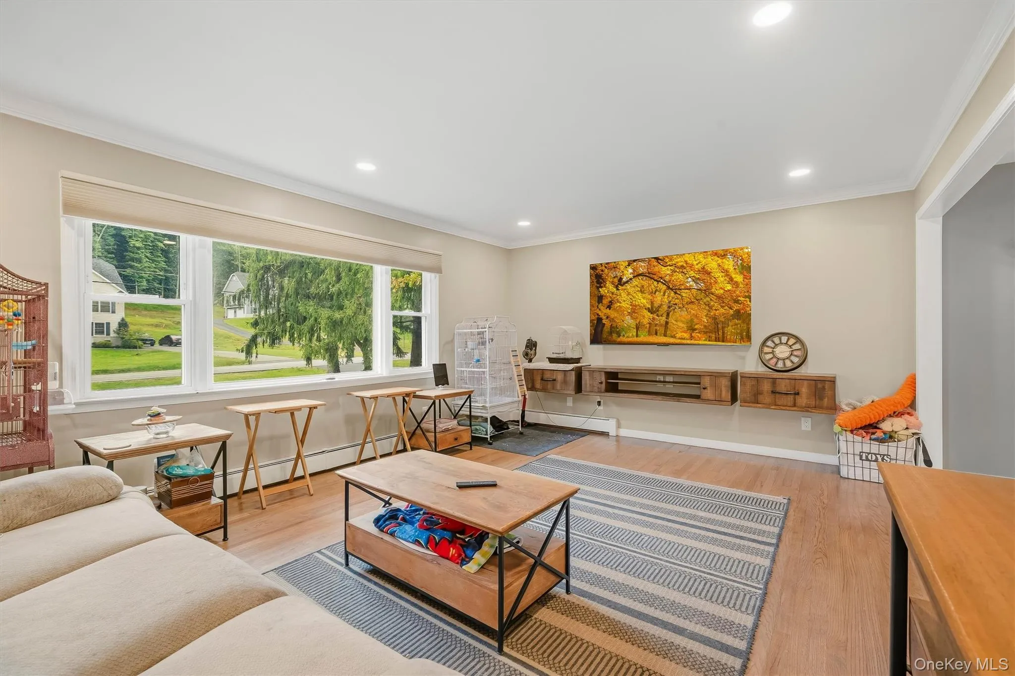 Recessed lighting, crown molding, wood-finish flooring, large picture window, and custom floating media console Recessed lighting, crown molding, wood-finish flooring, large picture window, and custom floating media console