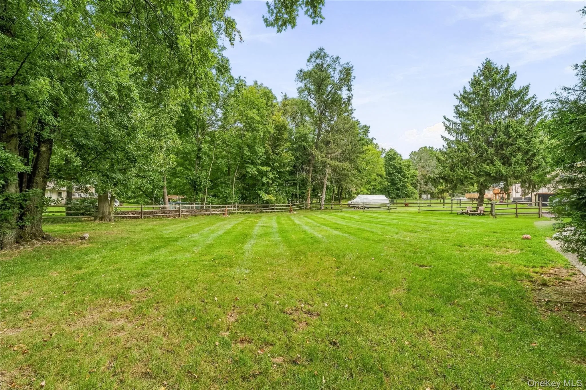 Expansive green lawn with mature trees and perimeter fencing Expansive green lawn with mature trees and perimeter fencing