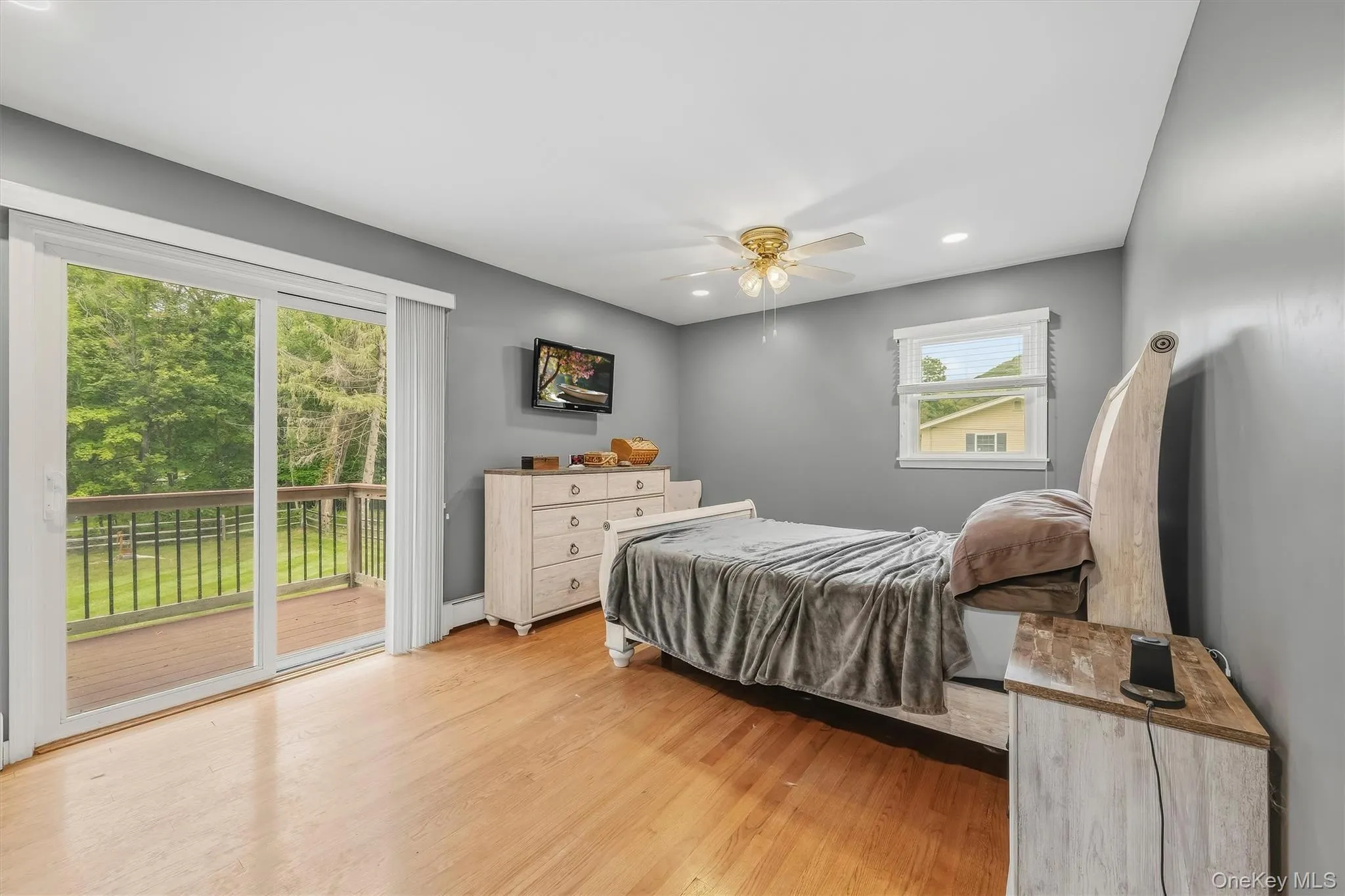 Sliding glass door leading to an outdoor deck, recessed lighting, wood-finish flooring, and a ceiling fan with integrated lighting Sliding glass door leading to an outdoor deck, recessed lighting, wood-finish flooring, and a ceiling fan with integrated lighting