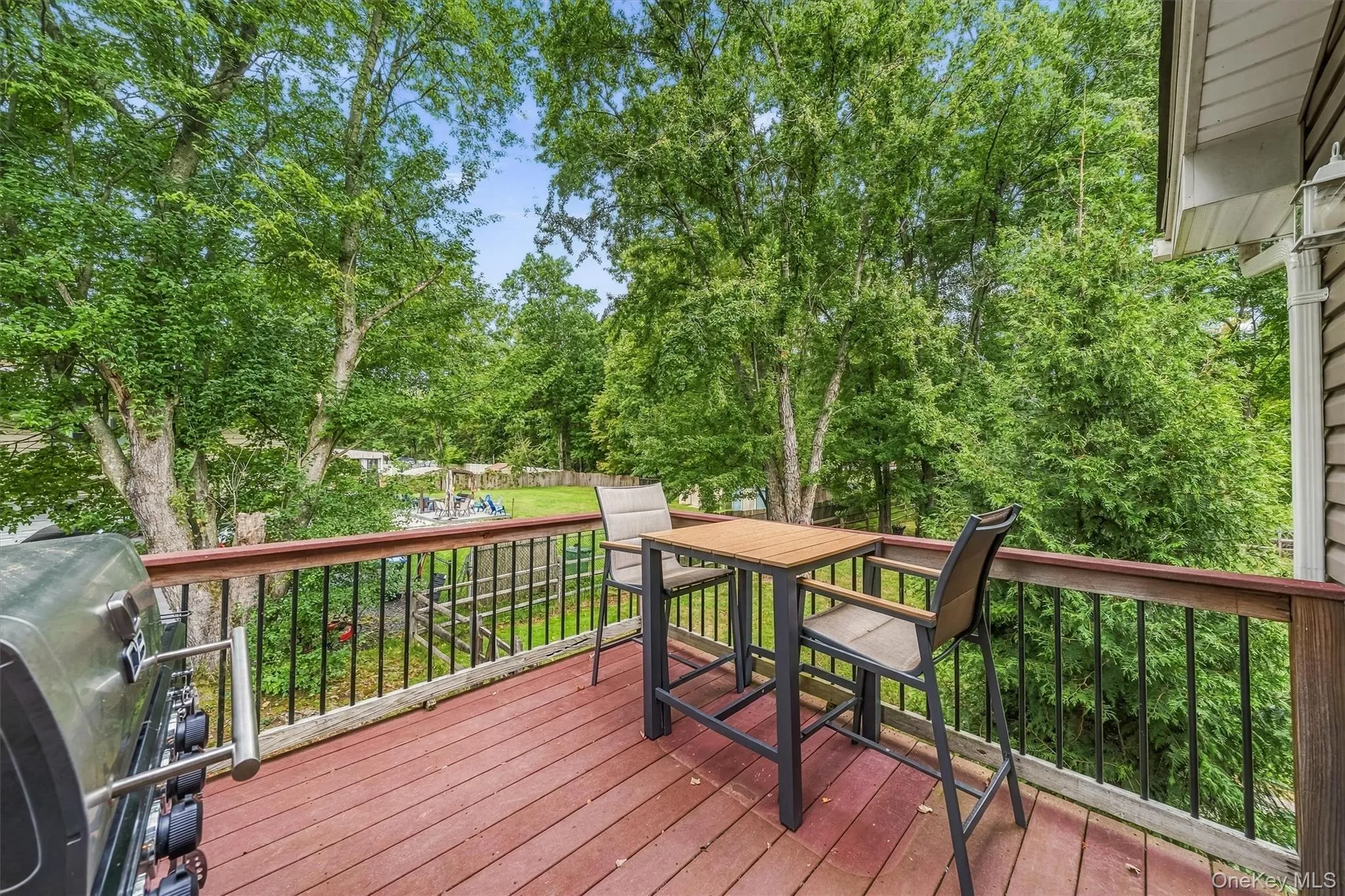Expansive outdoor deck with red-stained wood flooring and black metal railings Expansive outdoor deck with red-stained wood flooring and black metal railings