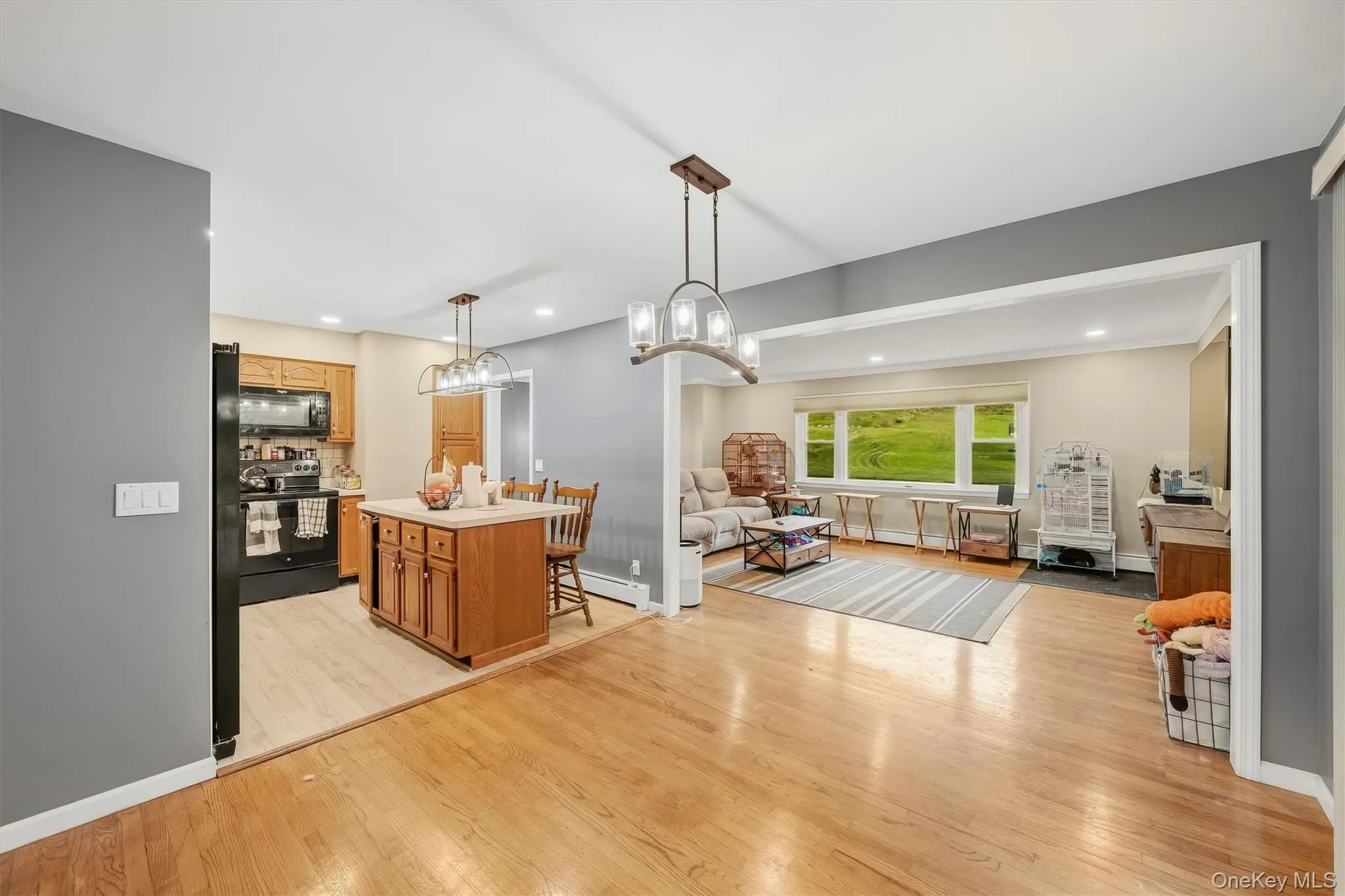 Wood-finish flooring throughout, with a kitchen island featuring wood cabinetry Wood-finish flooring throughout, with a kitchen island featuring wood cabinetry