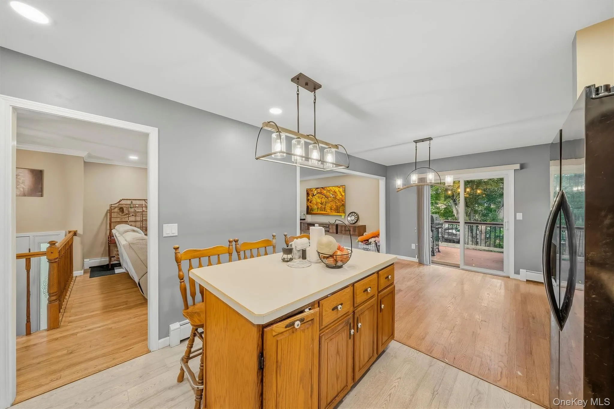 Kitchen island with wood-finish cabinetry and light-toned countertop, complemented by modern overhead lighting Kitchen island with wood-finish cabinetry and light-toned countertop, complemented by modern overhead lighting