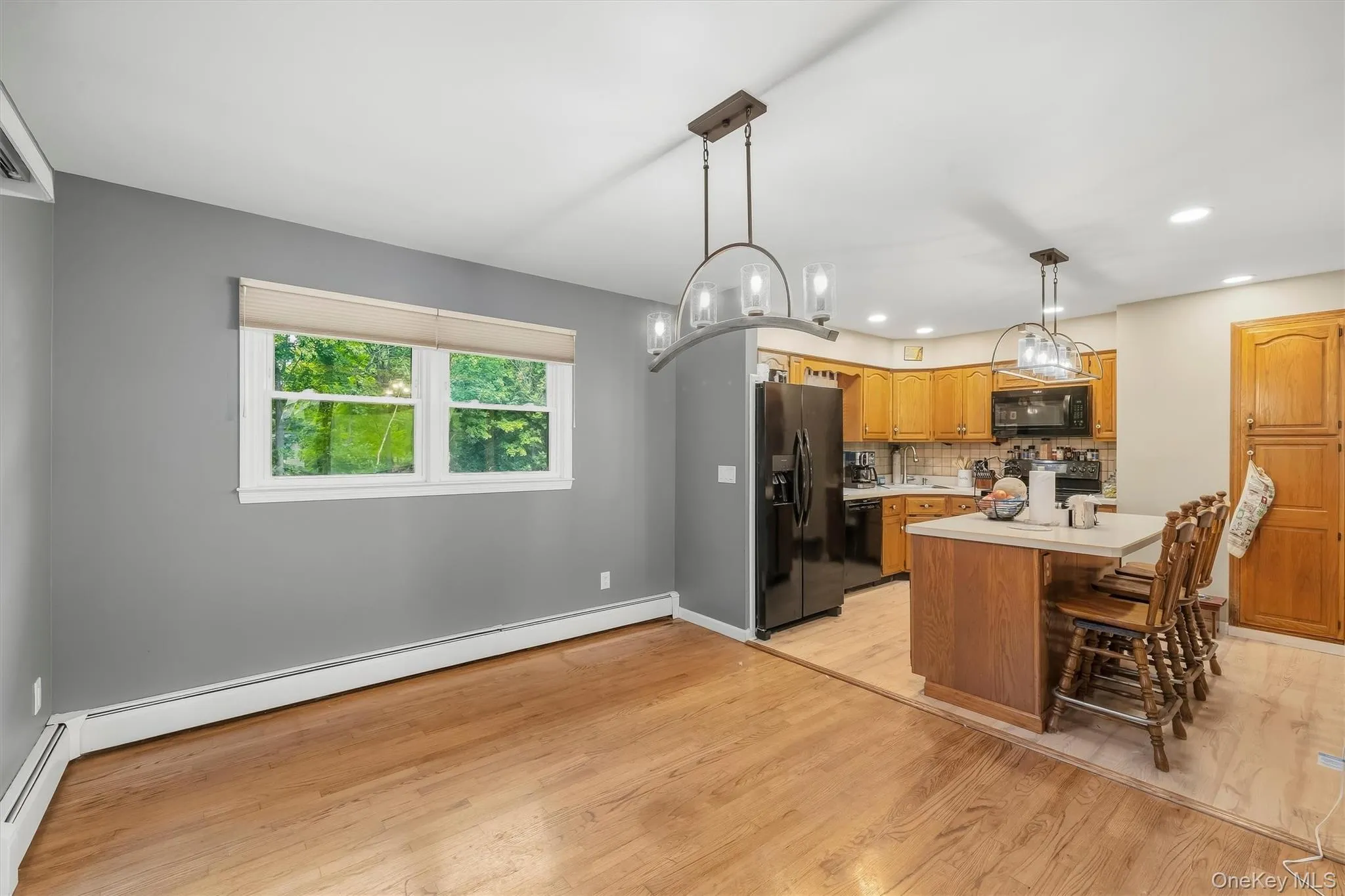 Hardwood flooring, kitchen island with counter seating, wood cabinetry, built-in microwave, and pendant lighting fixtures Hardwood flooring, kitchen island with counter seating, wood cabinetry, built-in microwave, and pendant lighting fixtures
