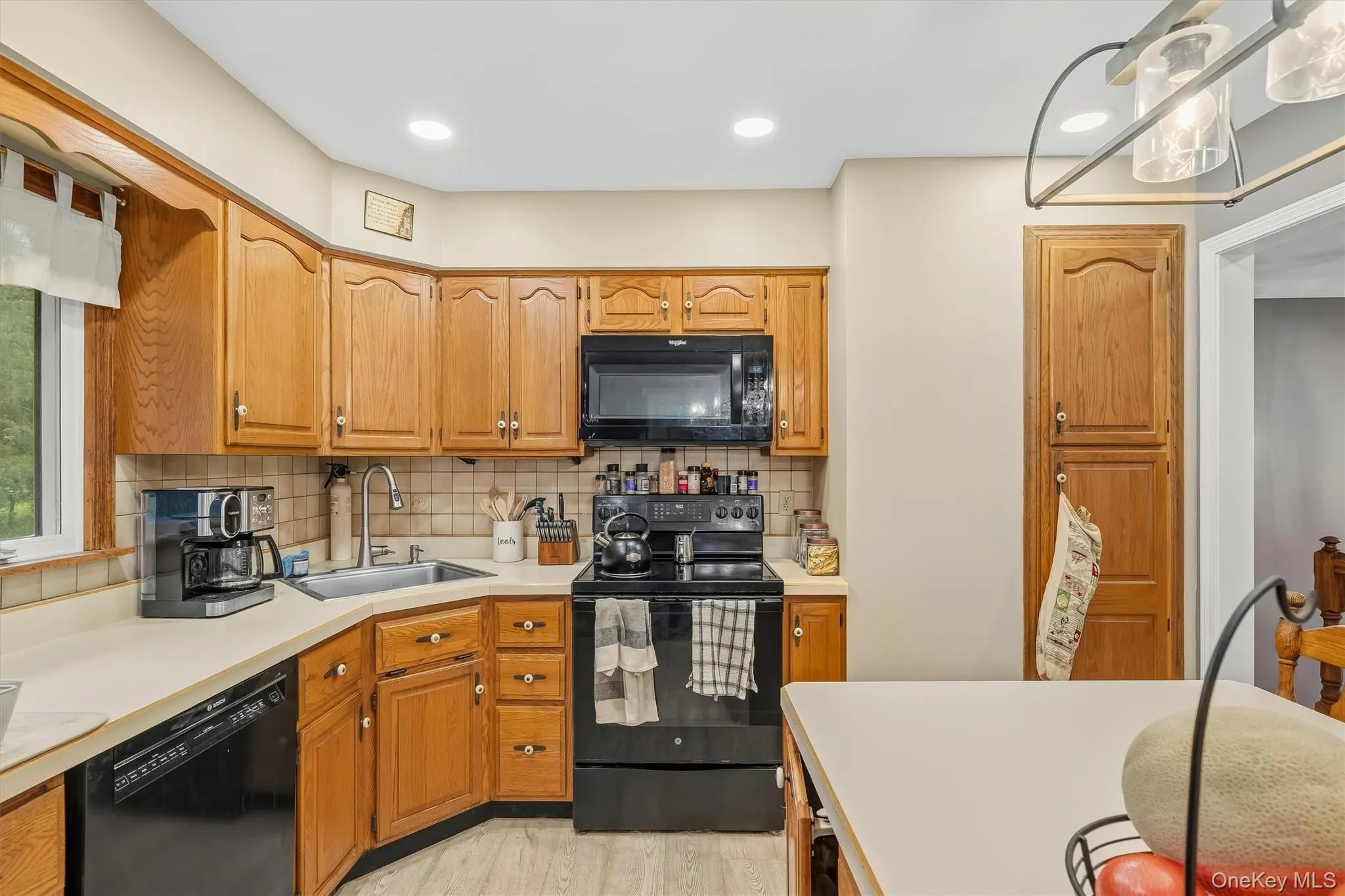 Kitchen featuring wood cabinetry, black appliances, a tile backsplash, and recessed lighting Kitchen featuring wood cabinetry, black appliances, a tile backsplash, and recessed lighting