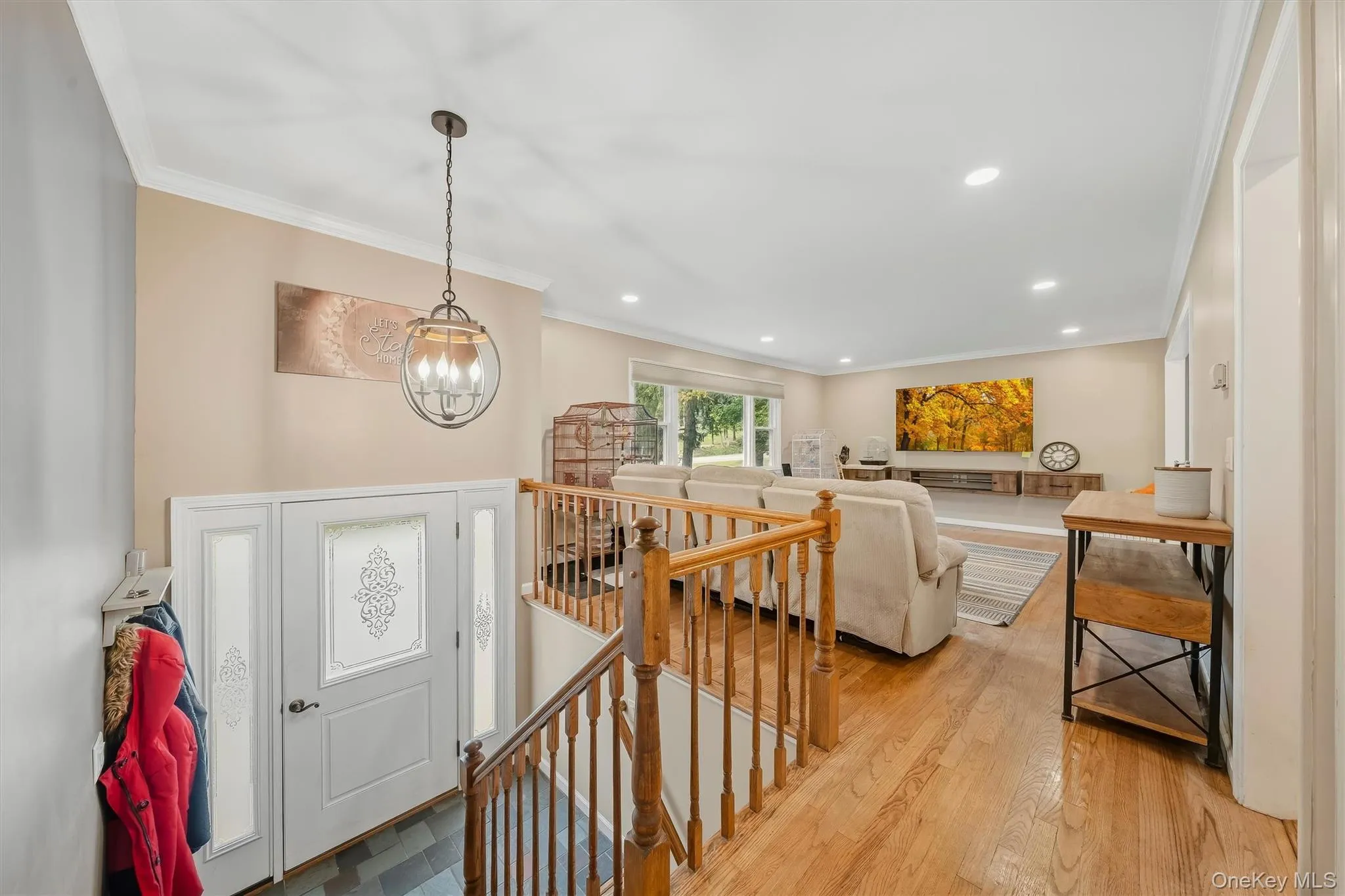 Hardwood flooring, white crown molding, recessed lighting, white entry door with decorative glass panels, and a wood railing Hardwood flooring, white crown molding, recessed lighting, white entry door with decorative glass panels, and a wood railing