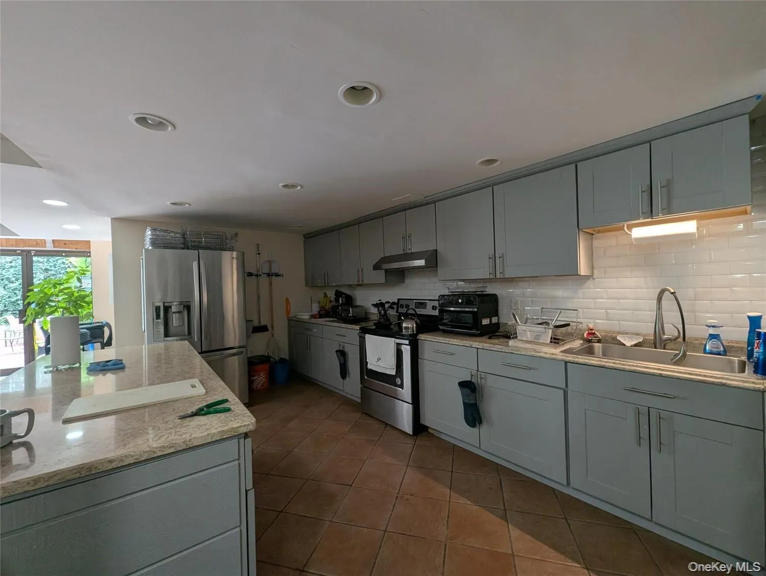 Kitchen featuring light blue gray cabinetry, stainless steel appliances, a subway tile backsplash, and recessed lighting Kitchen featuring light blue gray cabinetry, stainless steel appliances, a subway tile backsplash, and recessed lighting
