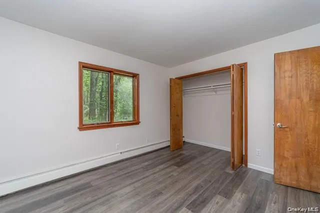Wood-finish flooring, white walls, and a wood-framed window Wood-finish flooring, white walls, and a wood-framed window