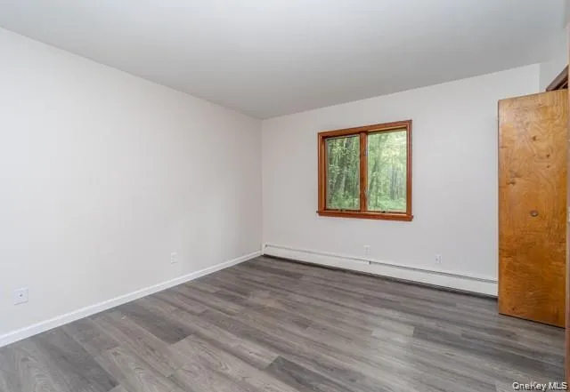 Wood-finish flooring, white walls, and a wood-framed window Wood-finish flooring, white walls, and a wood-framed window