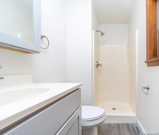 Wood-finish flooring, integrated sink with vanity, wall-mounted mirror cabinet, and a stall shower with brushed nickel fixtures Wood-finish flooring, integrated sink with vanity, wall-mounted mirror cabinet, and a stall shower with brushed nickel fixtures