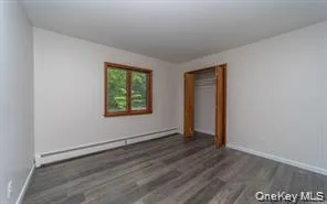Wood-finish flooring, white walls, and a window with wood trim Wood-finish flooring, white walls, and a window with wood trim
