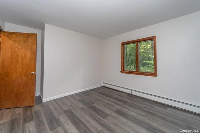 Wood-finish flooring with a rectangular window featuring wood trim, and a warm wood door Wood-finish flooring with a rectangular window featuring wood trim, and a warm wood door
