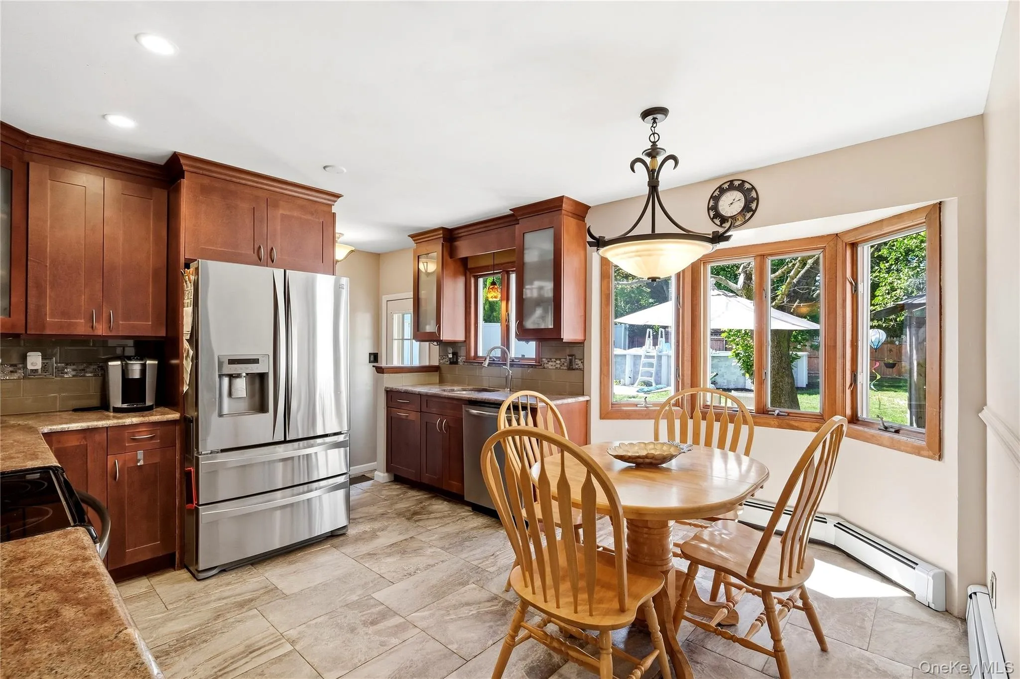 This eat in kitchen has gorgeous hardwood cabinetry, stainless steel refrigerator, tiled flooring, bay window, and recessed lighting This eat in kitchen has gorgeous hardwood cabinetry, stainless steel refrigerator, tiled flooring, bay window, and recessed lighting