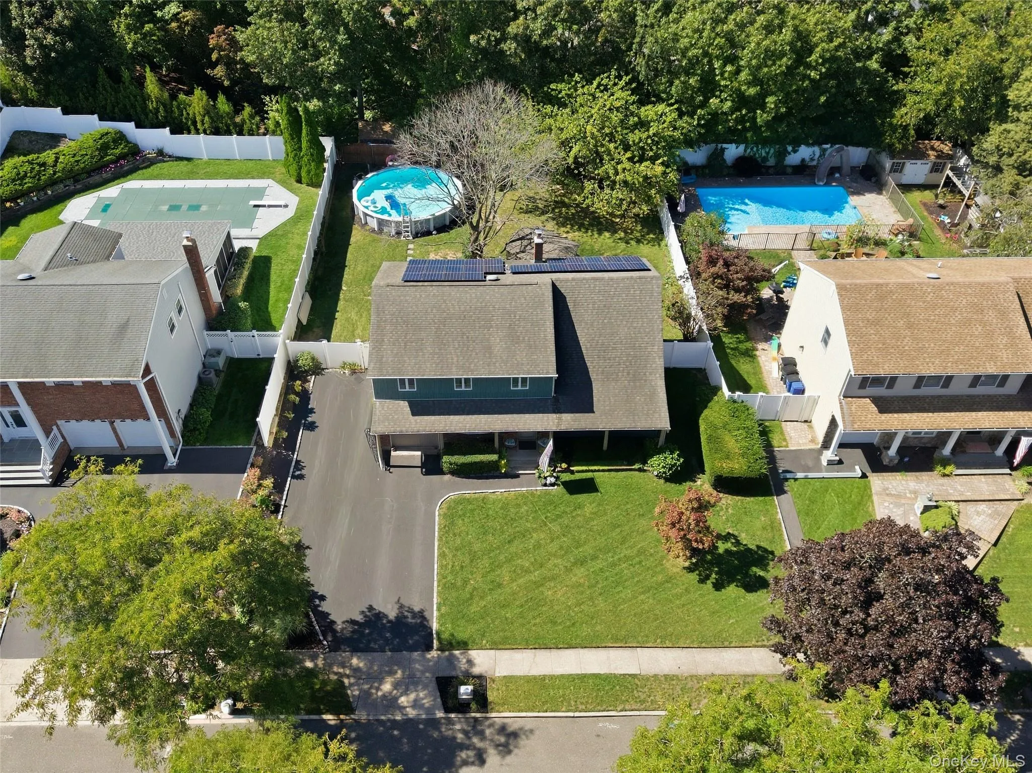 Front-facing two-story residence with a paved driveway, solar panels, and a well-maintained lawn Front-facing two-story residence with a paved driveway, solar panels, and a well-maintained lawn