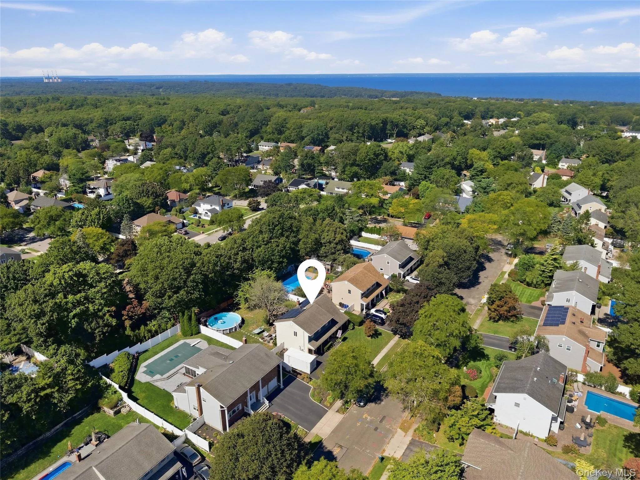 Residential neighborhood with mature trees, established properties, and distant water scenery Residential neighborhood with mature trees, established properties, and distant water scenery