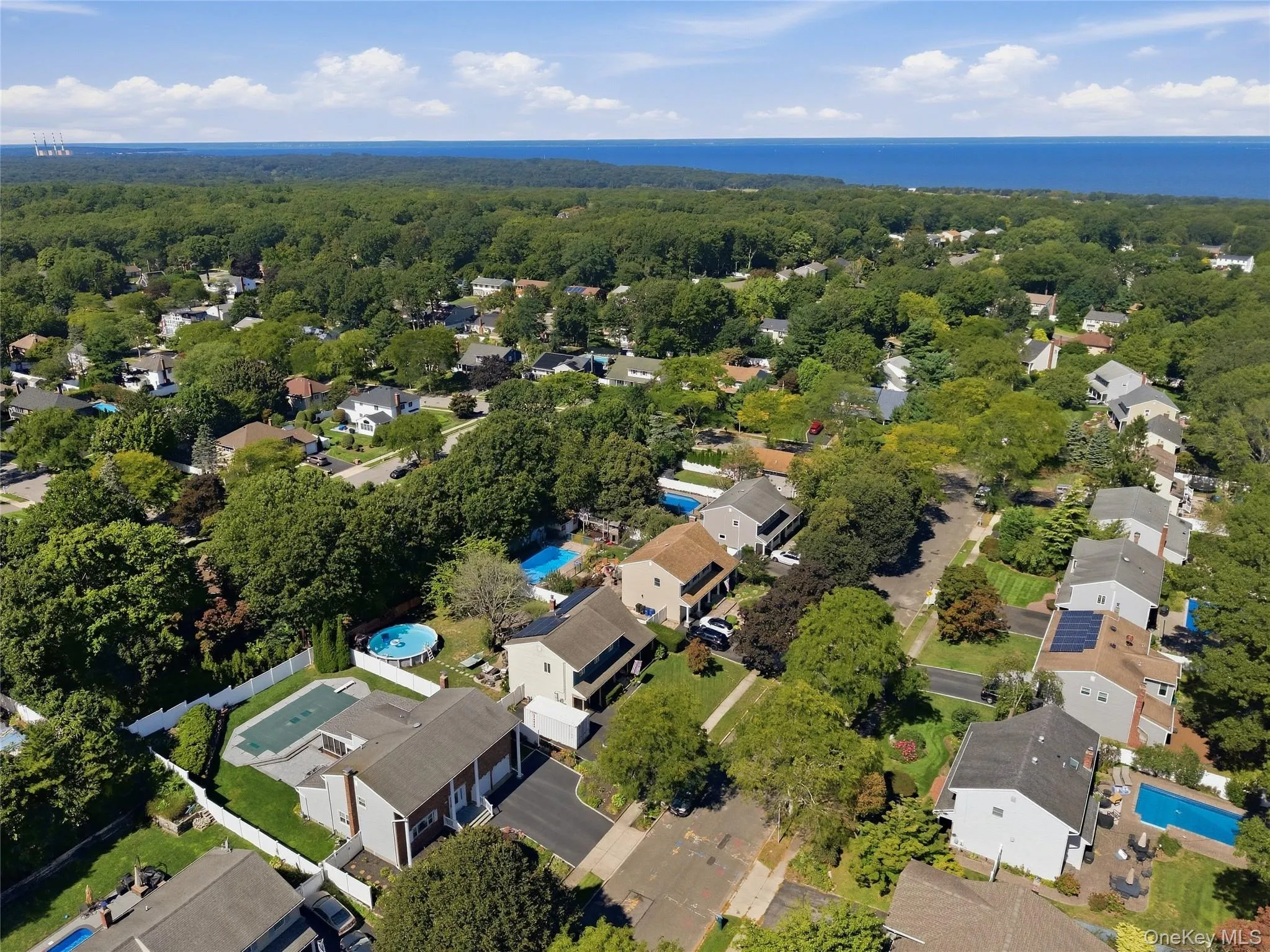 Residential neighborhood with mature trees, multiple properties featuring private pools, and a distant LI Sound horizon Residential neighborhood with mature trees, multiple properties featuring private pools, and a distant LI Sound horizon