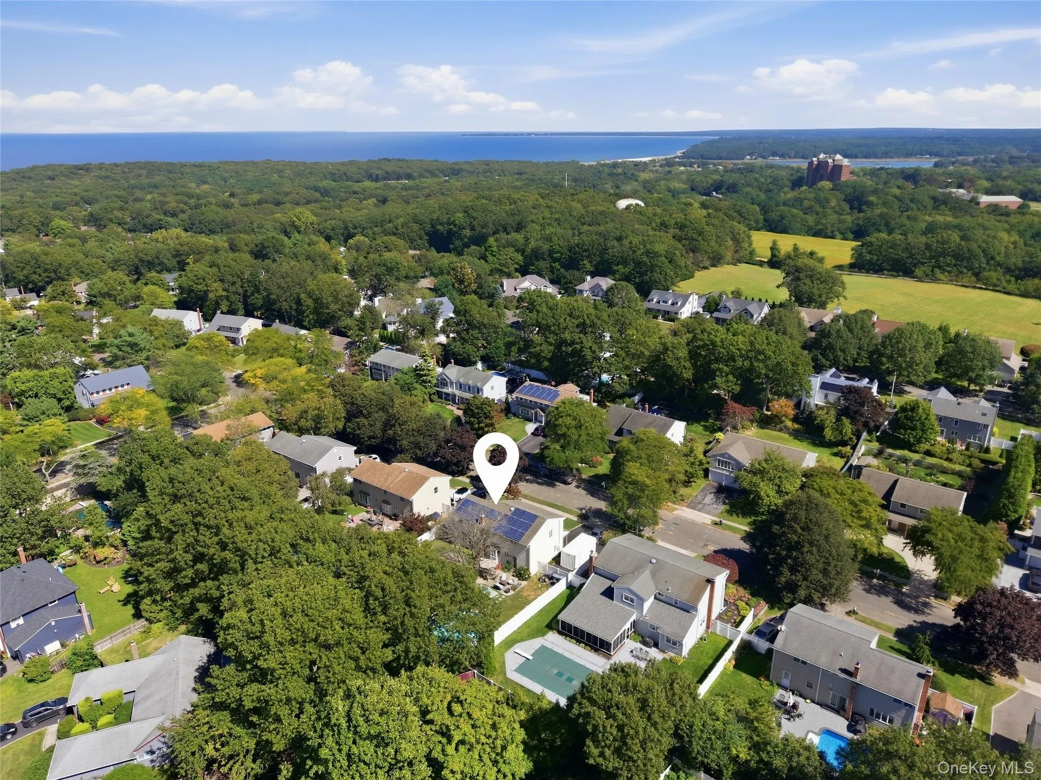 Aerial perspective with a distant body of water, surrounded by abundant mature trees and residential properties Aerial perspective with a distant body of water, surrounded by abundant mature trees and residential properties
