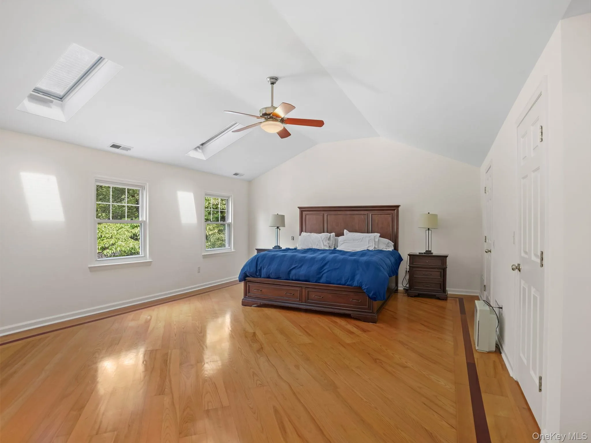 Bedroom with lofted ceiling, light wood-type flooring, a skylight, and a ceiling fan Bedroom with lofted ceiling, light wood-type flooring, a skylight, and a ceiling fan