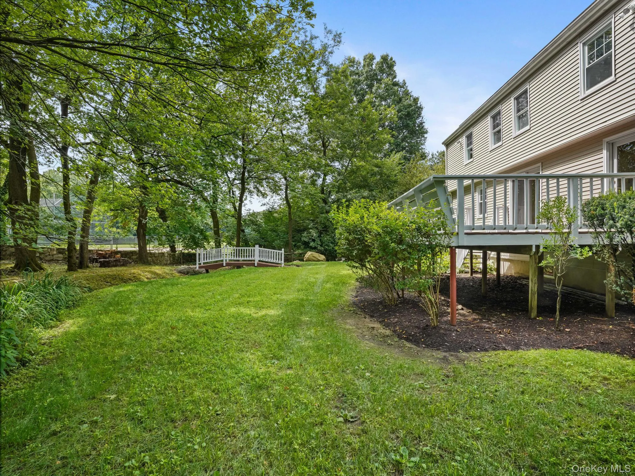 View of grassy yard with a deck and view of scattered trees View of grassy yard with a deck and view of scattered trees