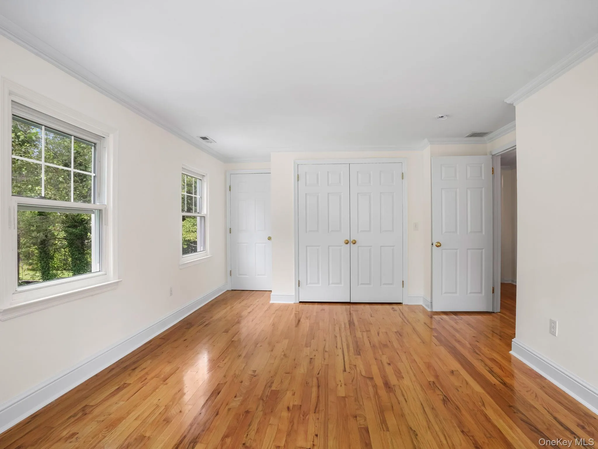 Unfurnished bedroom with wood finished floors, crown molding, and a closet Unfurnished bedroom with wood finished floors, crown molding, and a closet