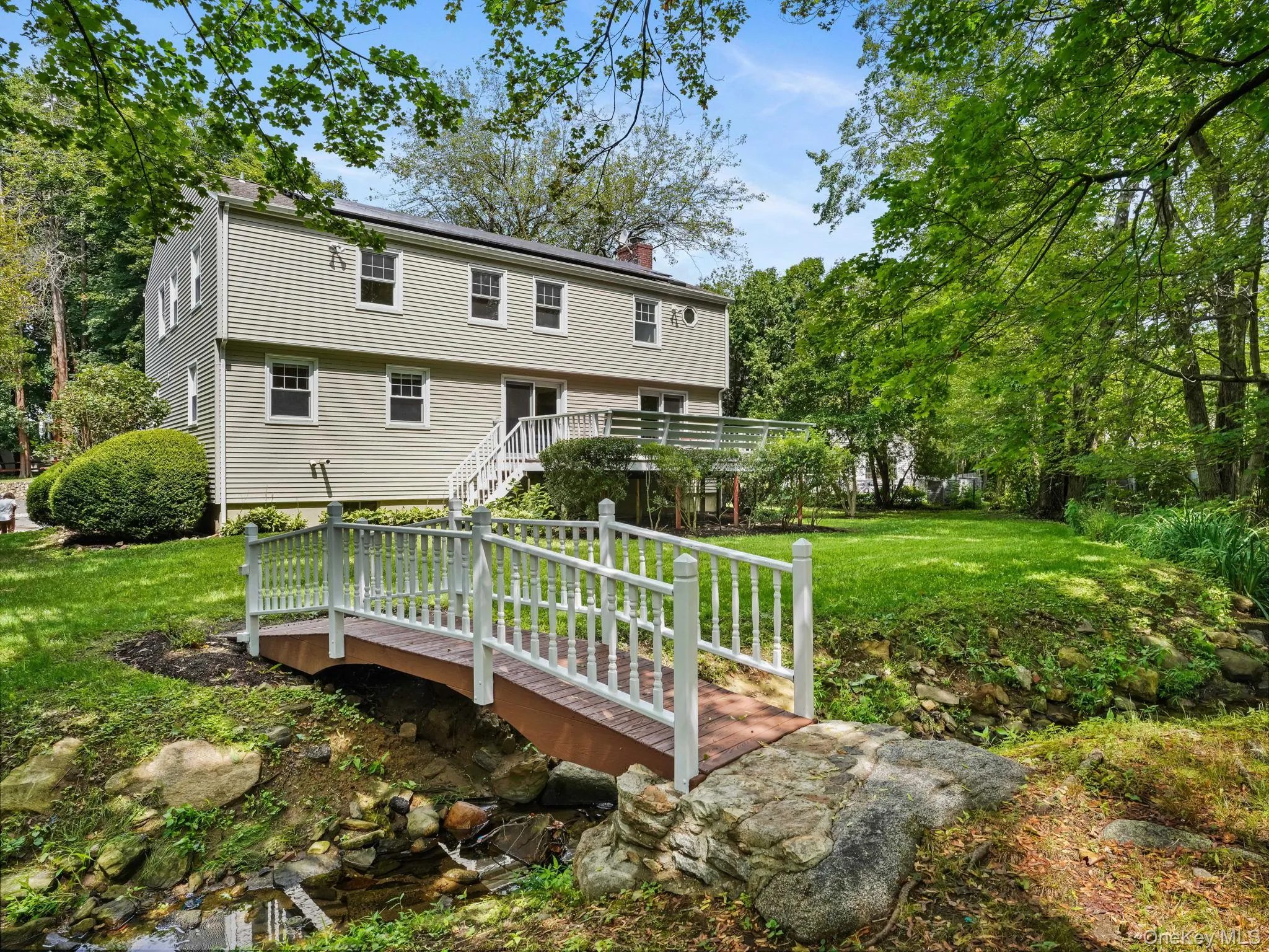 Back of house featuring stairs, a yard, a chimney, a wooden deck, and view of wooded area Back of house featuring stairs, a yard, a chimney, a wooden deck, and view of wooded area