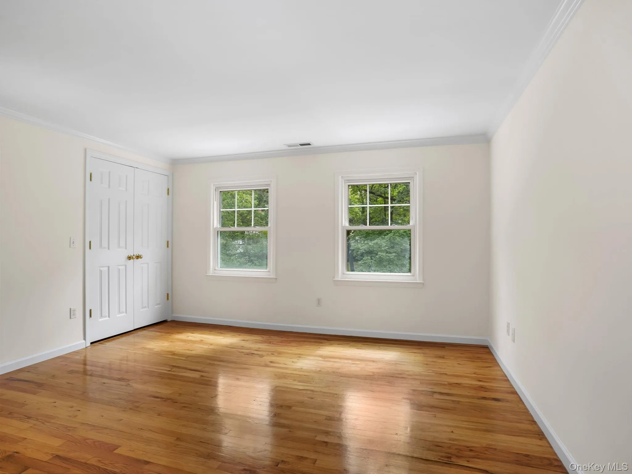 Unfurnished bedroom featuring light wood finished floors, a closet, and ornamental molding Unfurnished bedroom featuring light wood finished floors, a closet, and ornamental molding