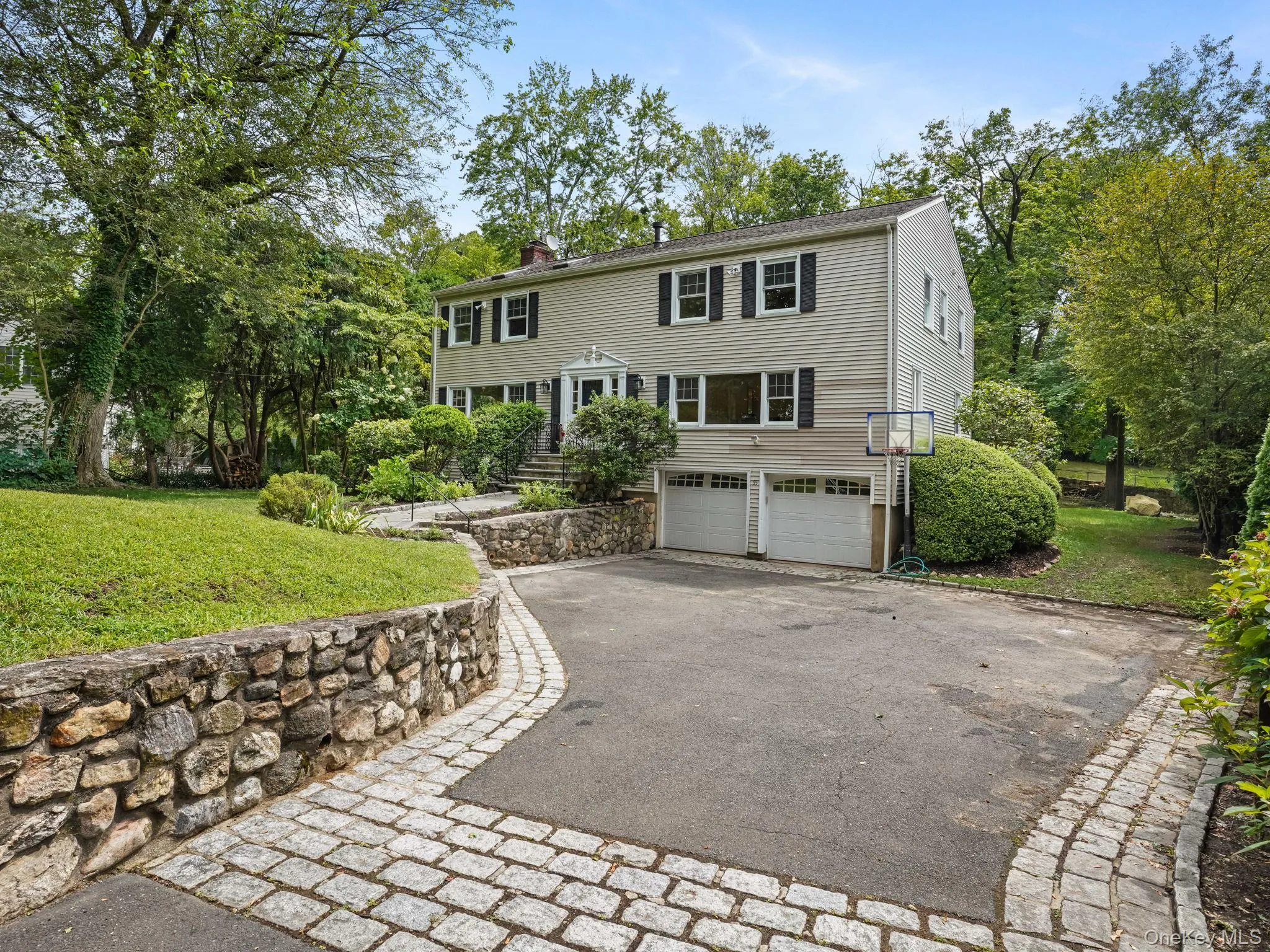 Colonial home with a chimney, driveway, a front yard, and an attached garage Colonial home with a chimney, driveway, a front yard, and an attached garage