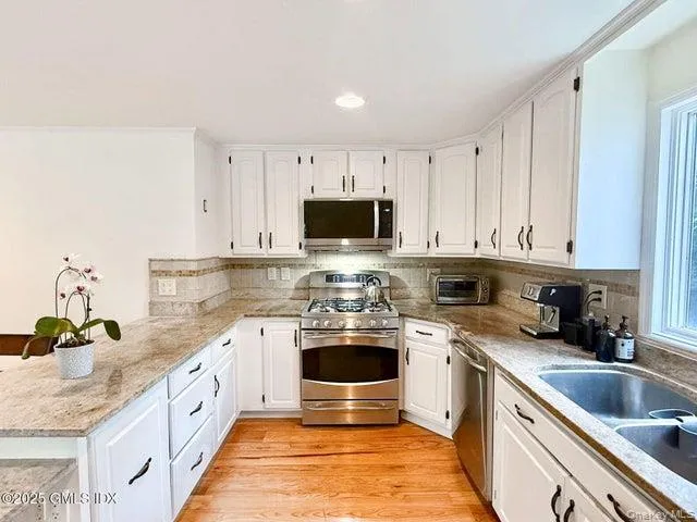 Kitchen with white cabinetry, backsplash, light stone countertops, and recessed lighting Kitchen with white cabinetry, backsplash, light stone countertops, and recessed lighting