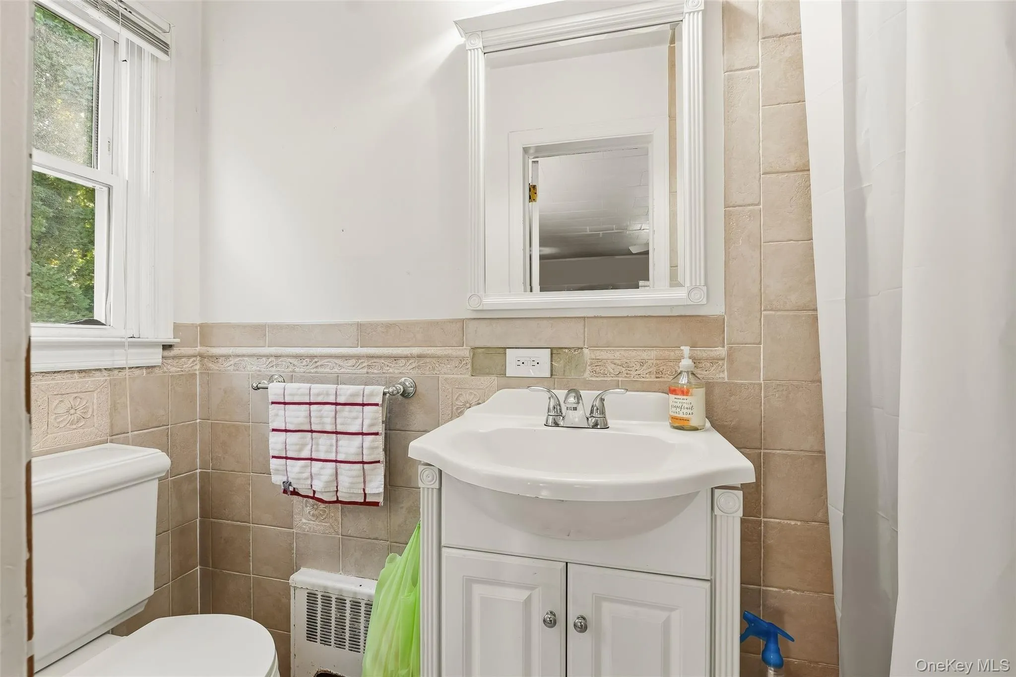 White pedestal sink with chrome faucet, framed mirror, and tiled walls White pedestal sink with chrome faucet, framed mirror, and tiled walls