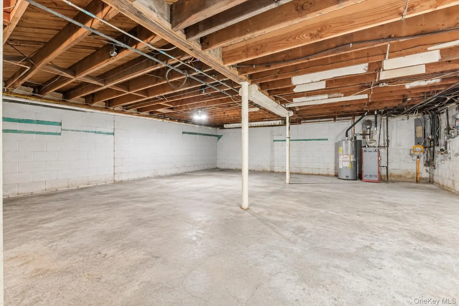 Expansive unfinished basement featuring a concrete floor, exposed wood beams, and painted block walls Expansive unfinished basement featuring a concrete floor, exposed wood beams, and painted block walls