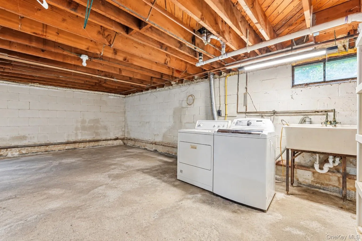 Laundry area featuring a utility sink, a window, and exposed wood beam ceiling Laundry area featuring a utility sink, a window, and exposed wood beam ceiling